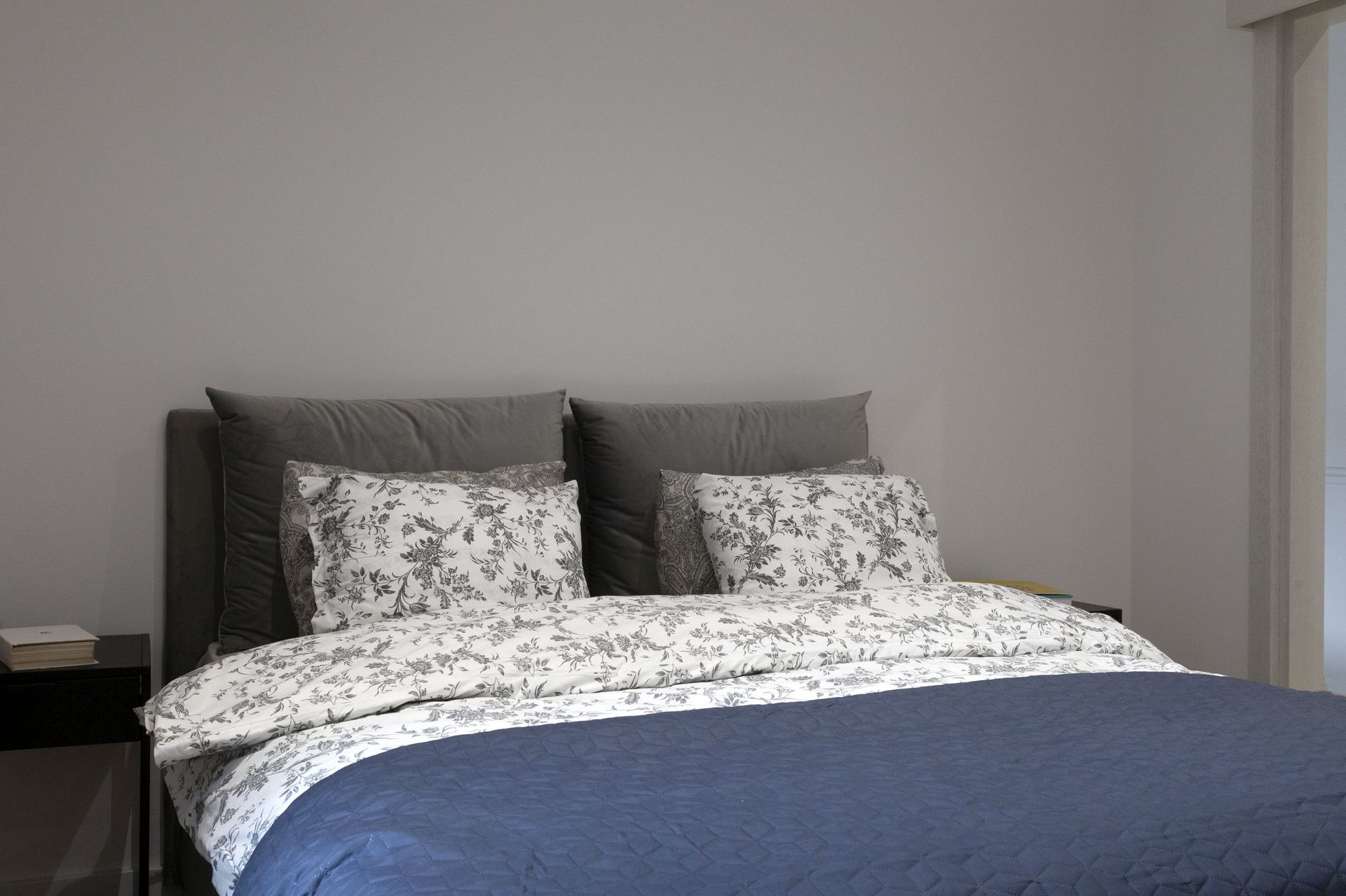 Modern bedroom in an apartment in Kotor, Montenegro: a double bed with a gray headboard and a blue bedspread.