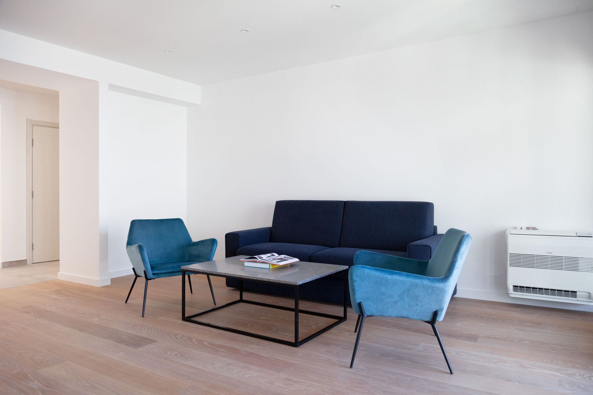Modern living room with a blue sofa and armchairs in an apartment in Kotor, Montenegro. Bright interior with parquet flooring.
