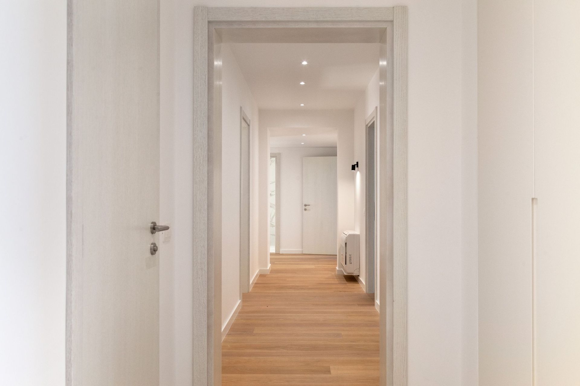 Bright hallway with wooden flooring and white doors in a modern apartment, Kotor, Montenegro.