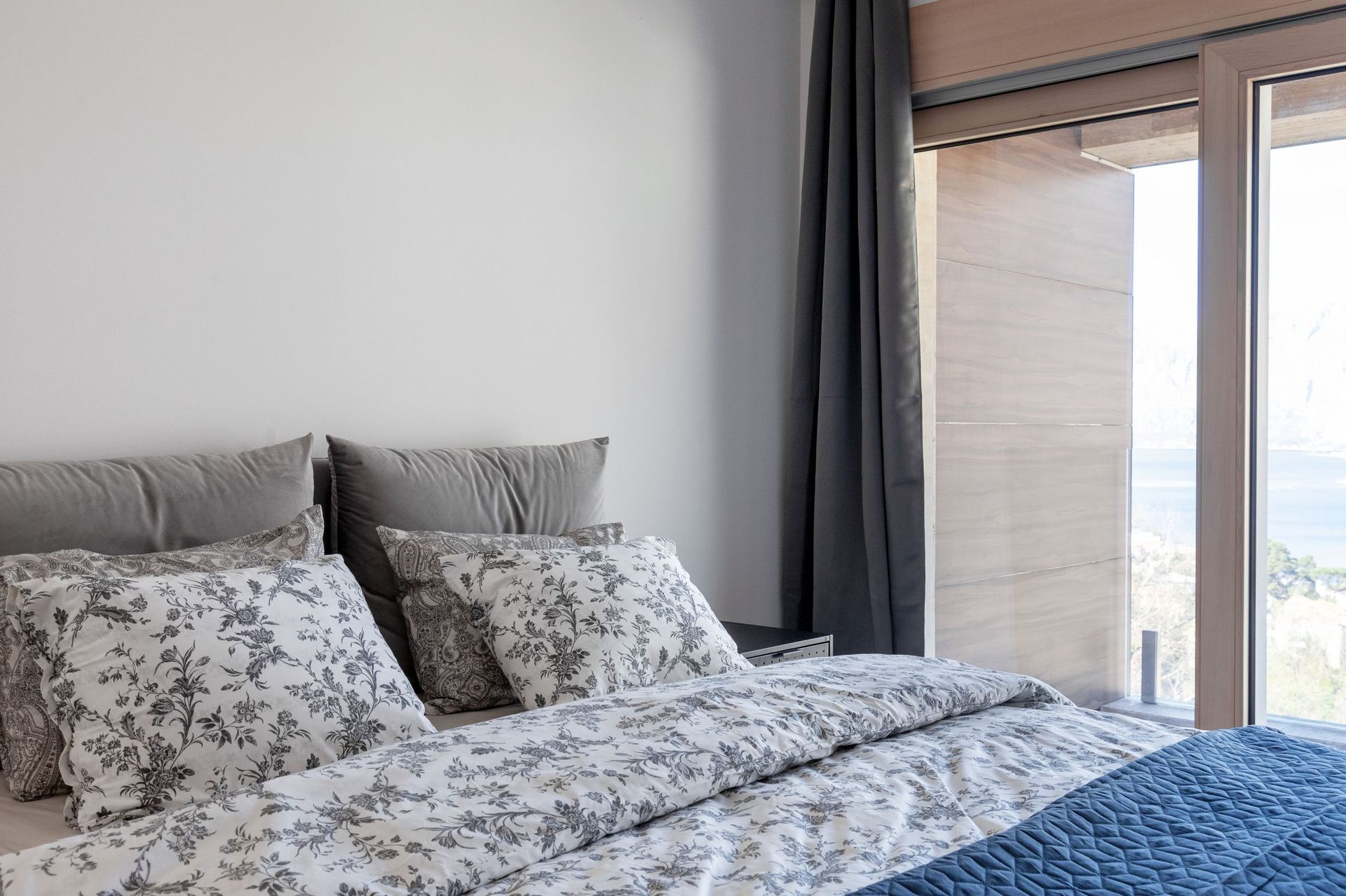 Modern bedroom in an apartment in Kotor, Montenegro, with a double bed and panoramic sea view from the window.