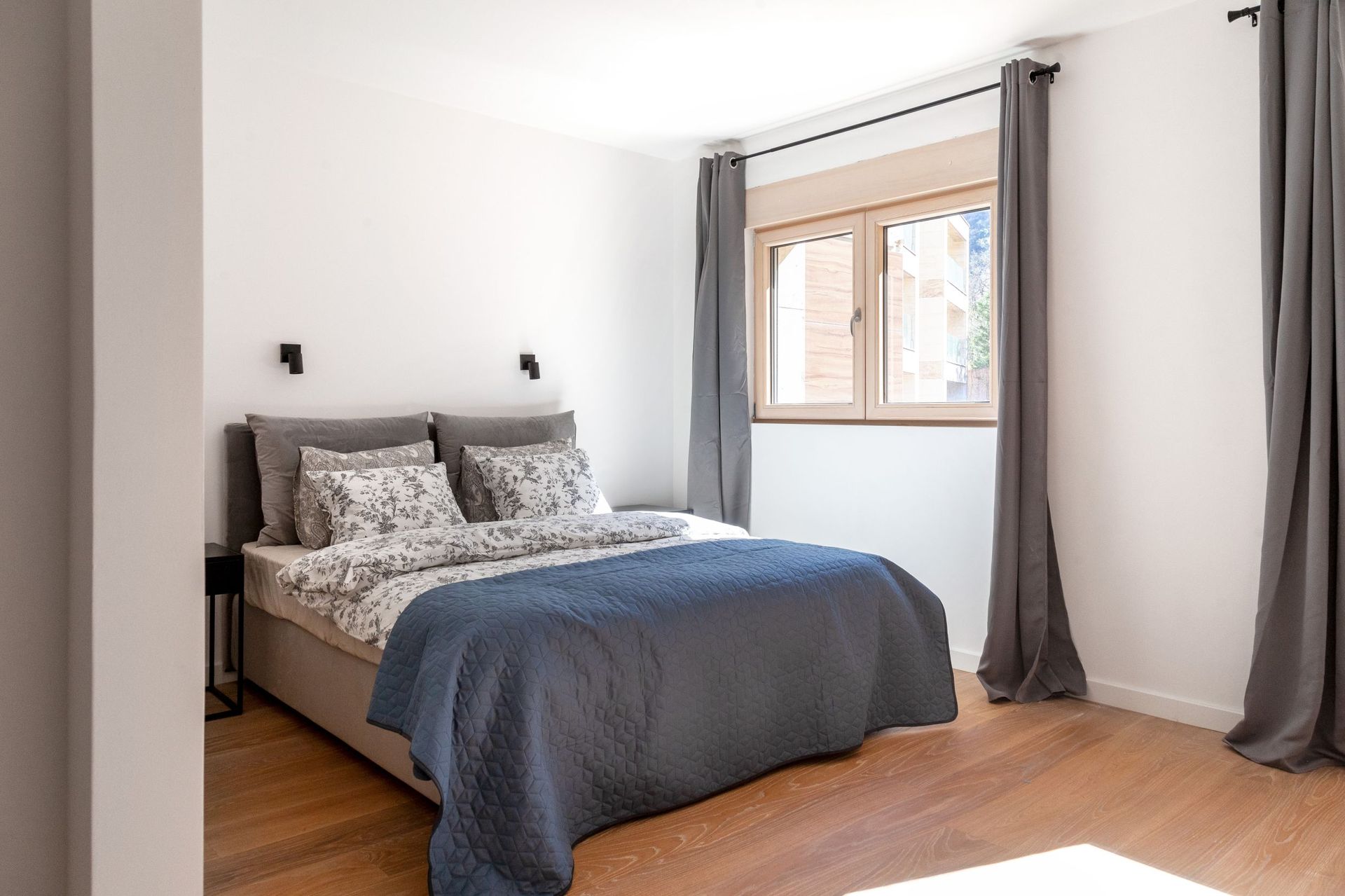 Bright bedroom with a double bed and wooden floor in an apartment in Kotor, Montenegro.