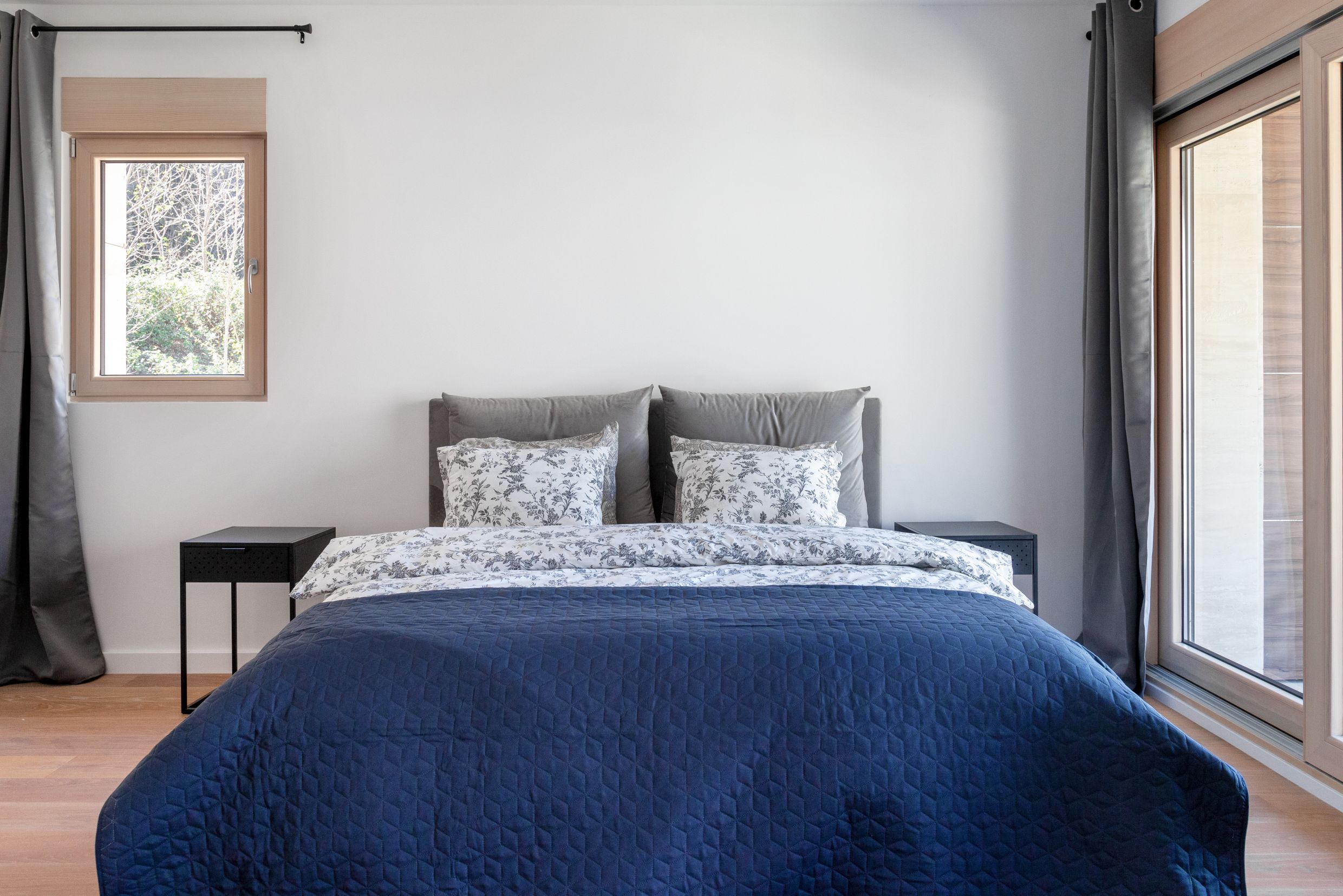 Modern bedroom with a double bed in an apartment in Kotor, Montenegro: panoramic windows and a bright interior.