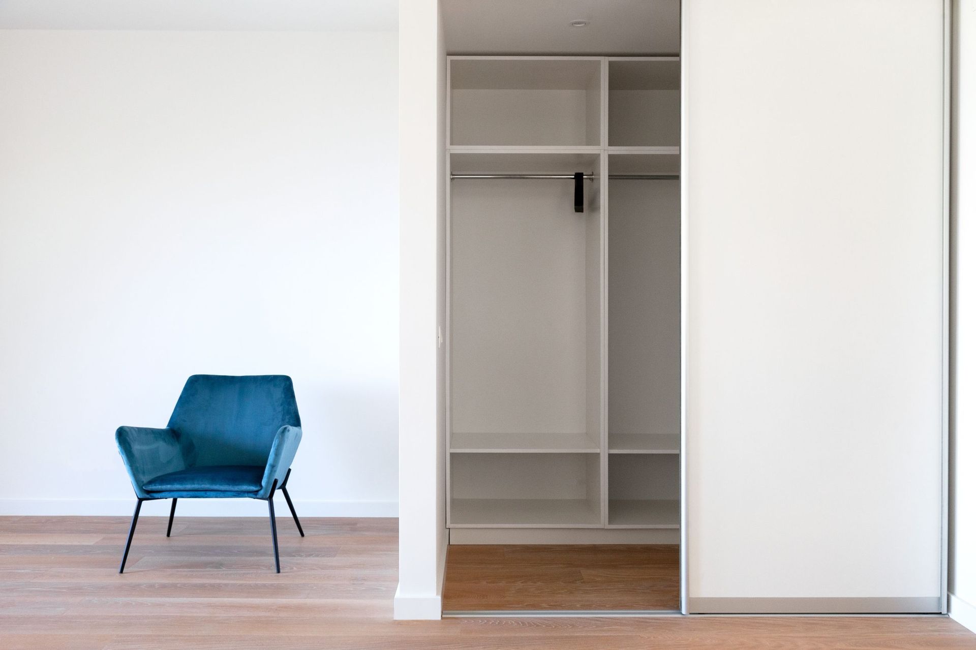Modern bedroom in an apartment in Kotor, Montenegro: blue velvet armchair, built-in wardrobe, and parquet floor.
