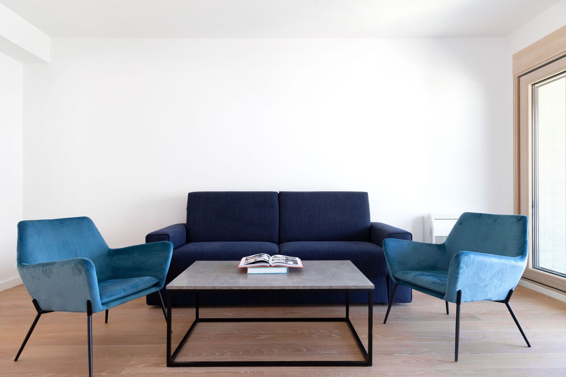Modern living room in an apartment in Kotor, Montenegro: blue sofa, armchairs, coffee table, and bright interior.