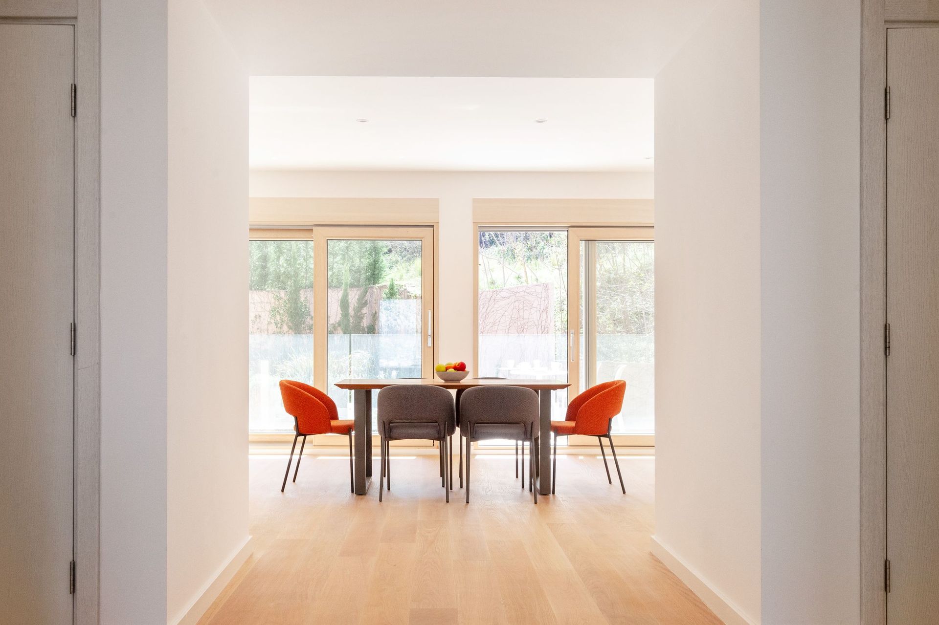 Modern dining area in an apartment in Kotor, Montenegro: a table with orange and gray chairs and panoramic windows.