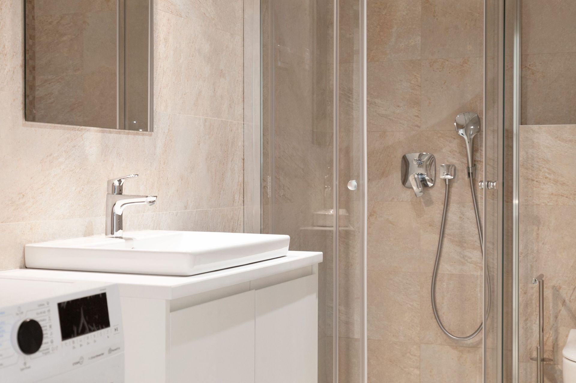 Modern bathroom in an apartment in Kotor, Montenegro: shower cabin, white vanity with sink, and tiled finish.