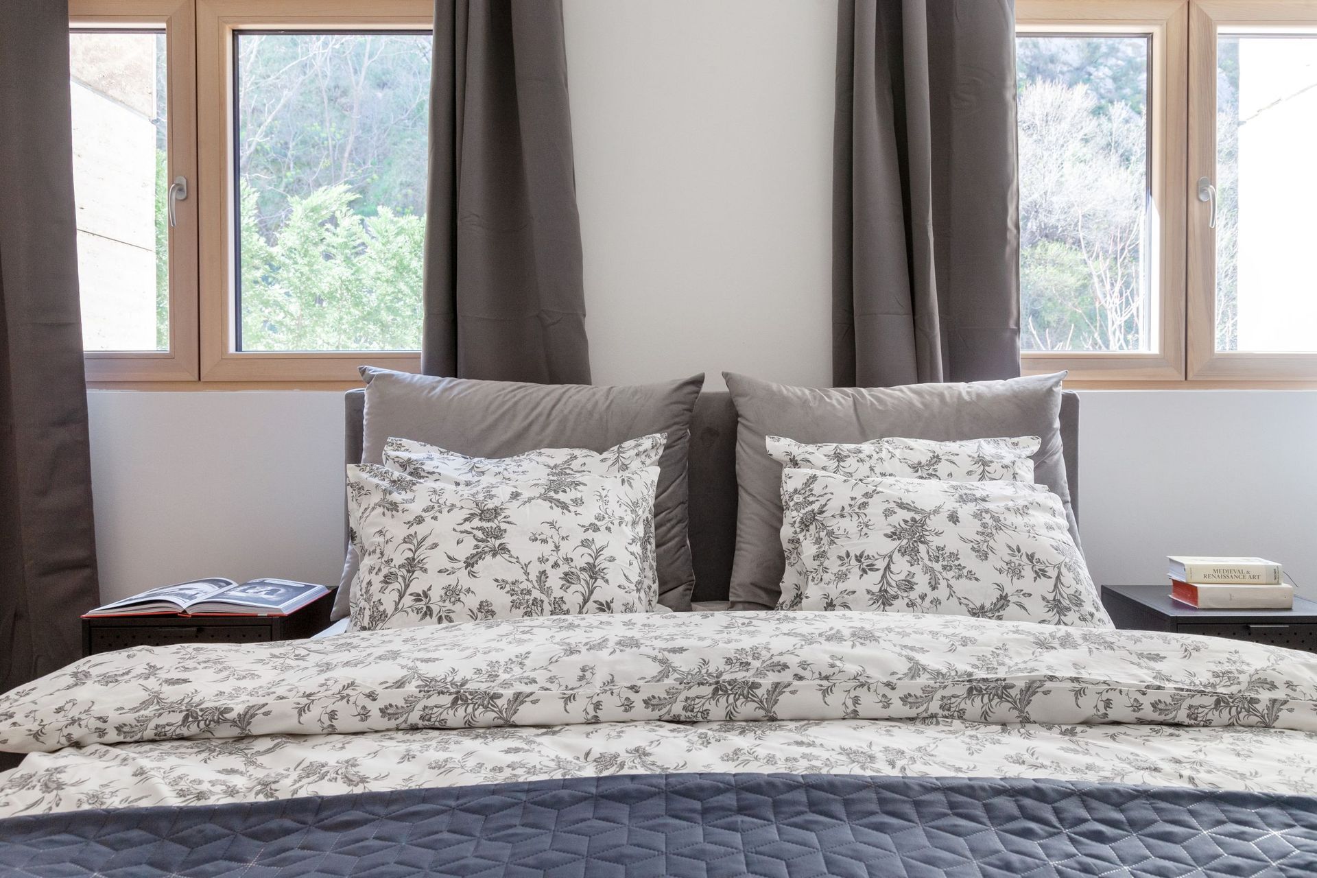 Cozy bedroom with a double bed in an apartment in Kotor, Montenegro, with greenery views from panoramic windows.