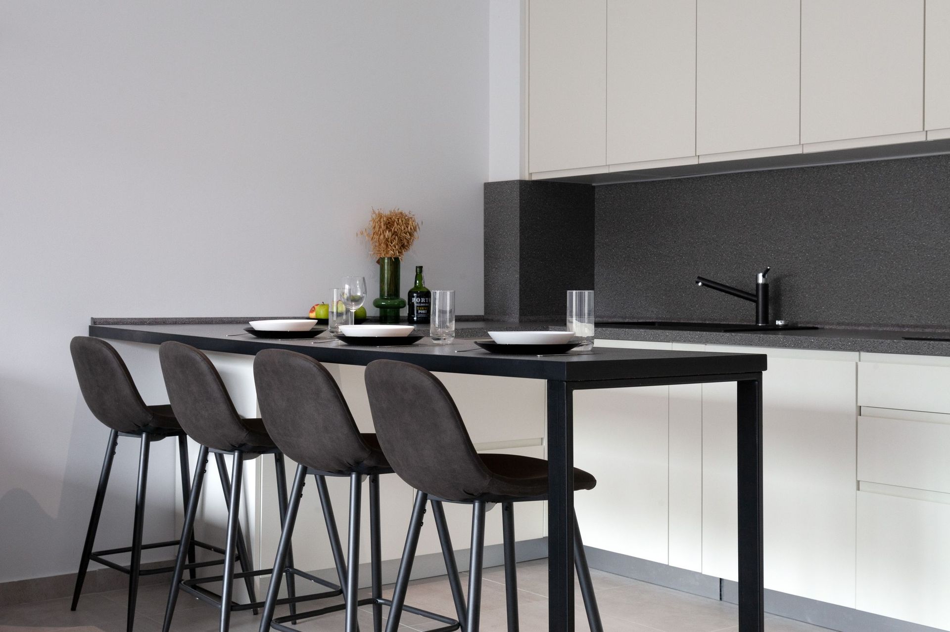 Modern kitchen in an apartment in Kotor, Montenegro: a breakfast bar, gray chairs, light cabinet fronts, and a dark countertop.