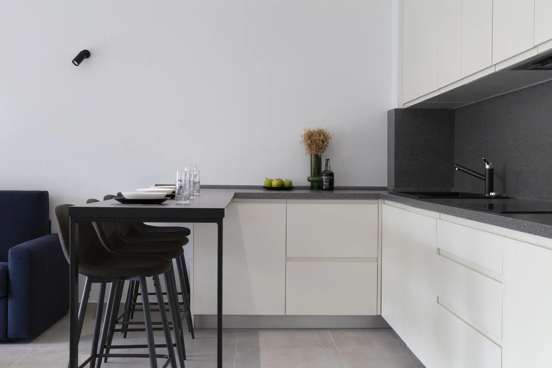 Modern kitchen with white cabinets, dark countertop, and a bar counter with stools.