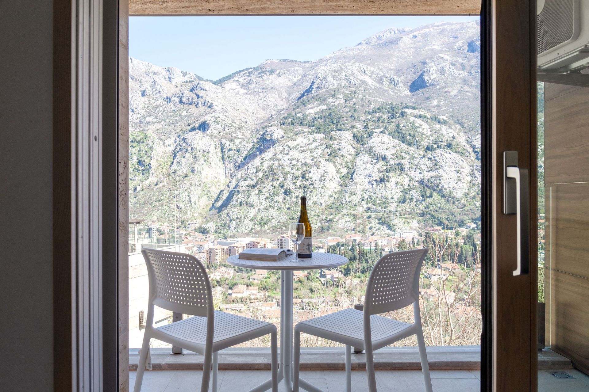 Balcony with white furniture and panoramic views of the mountains and the city of Kotor, Montenegro. Apartment No. 2562 with a terrace.