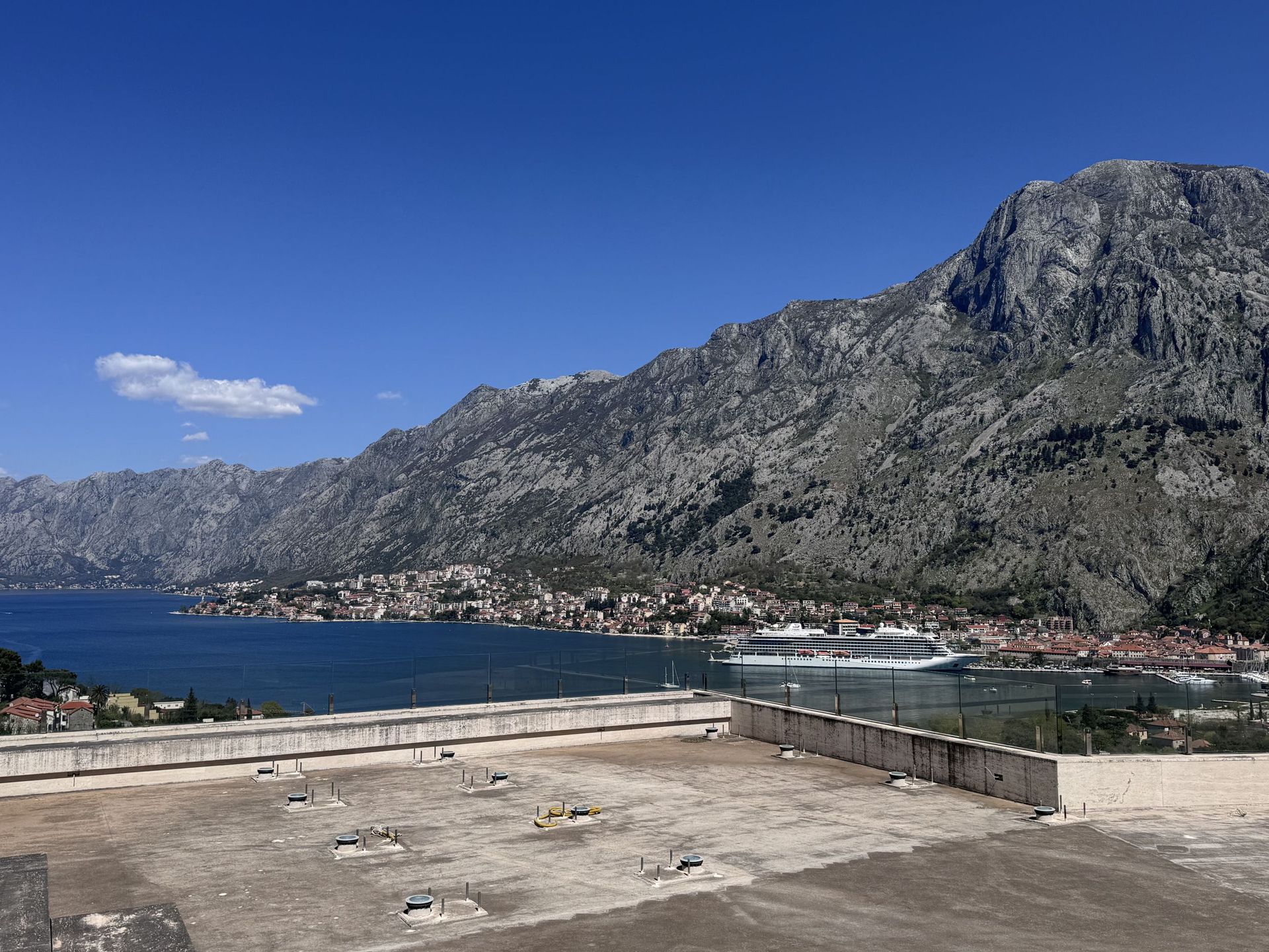Panoramic view of Kotor Bay and the mountains from the terrace of a duplex in Kotor, Montenegro, with a cruise ship on the water.