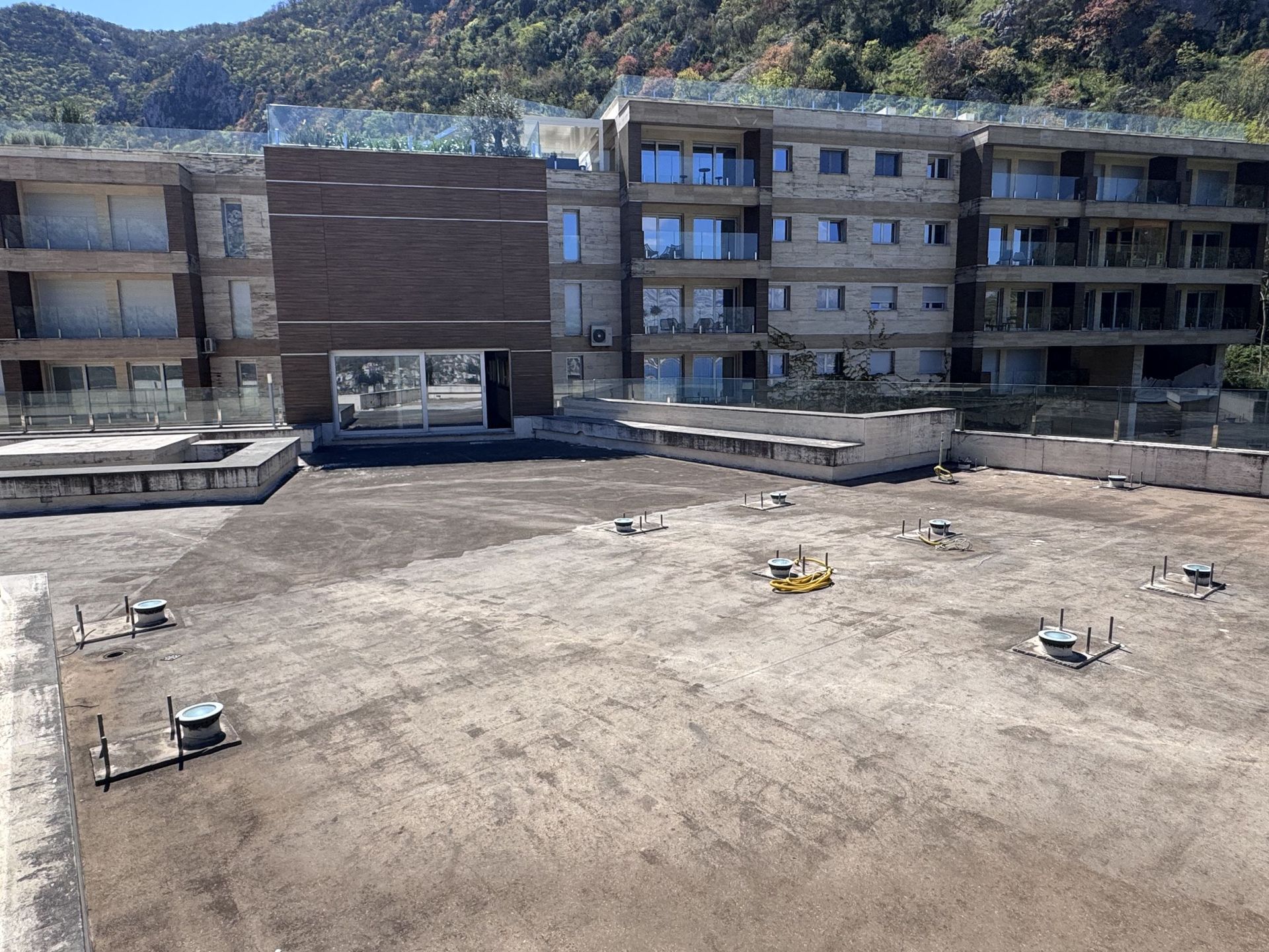 Open terrace of a modern residential complex in Kotor, Montenegro, with a view of the mountains and the building facade.