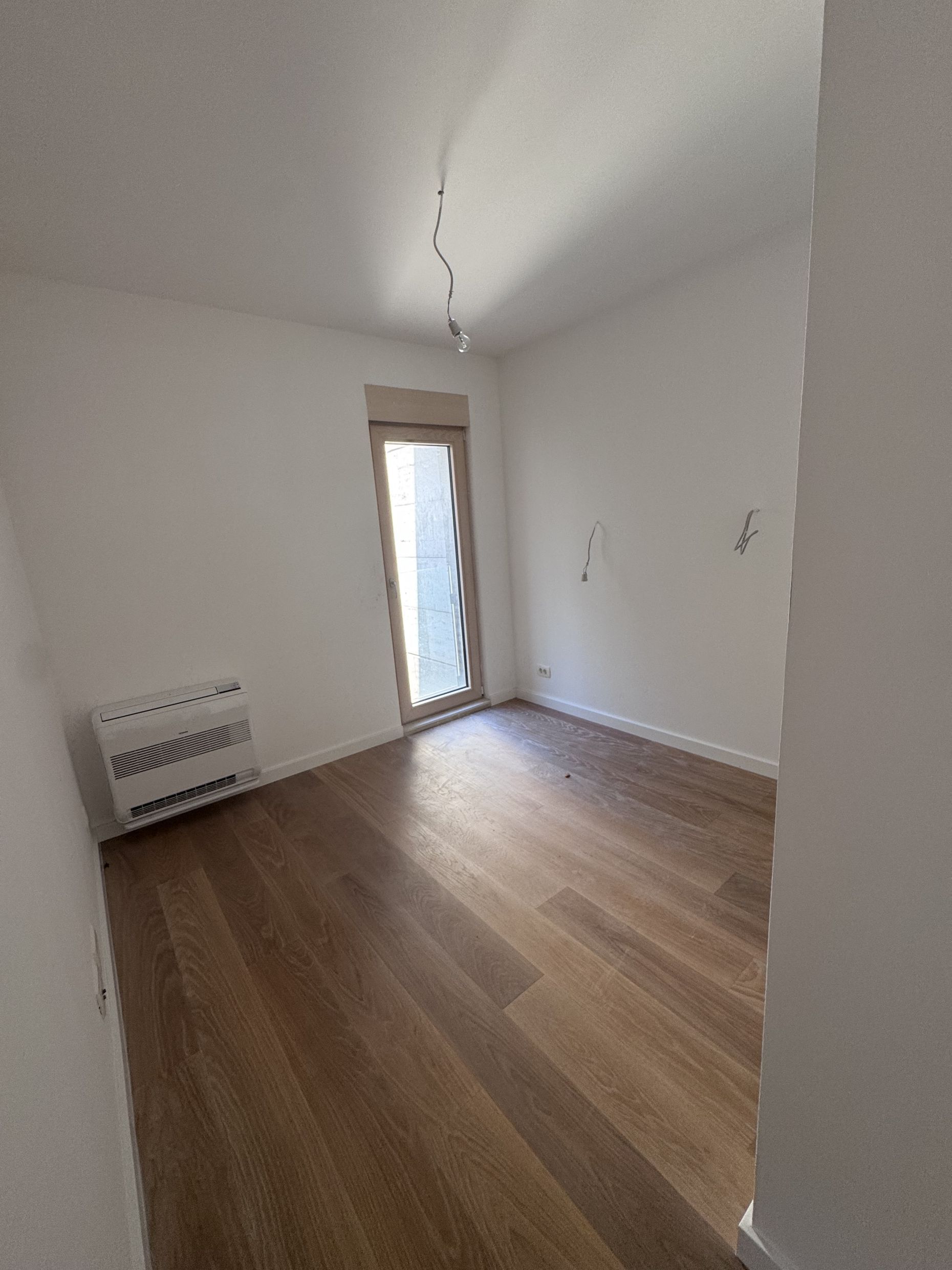 Bright bedroom in a duplex in Kotor, Montenegro: parquet floor, air conditioning, and access to the balcony, city view.