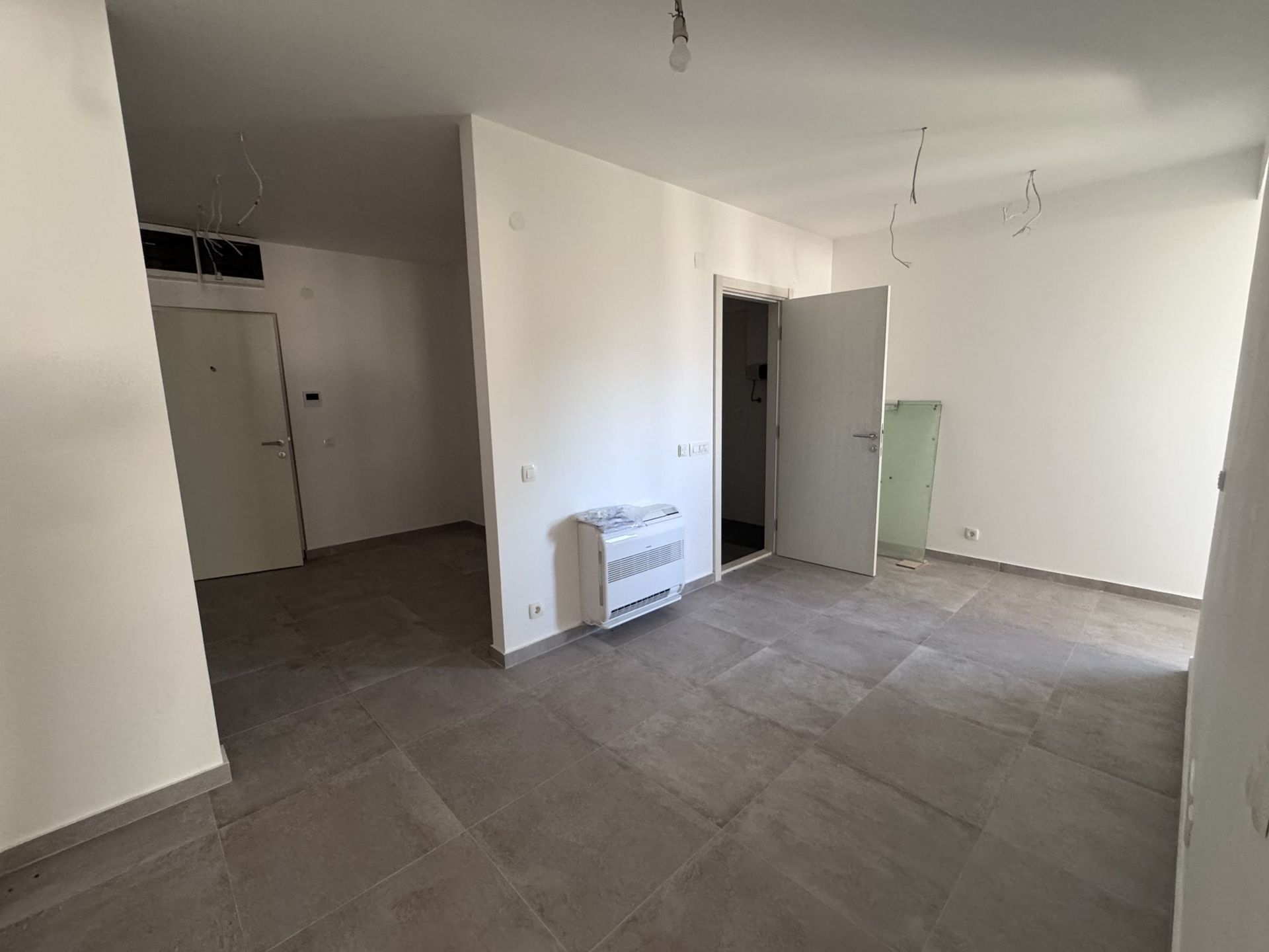 Living room in a new apartment in Kotor, Montenegro: light finishes, floor tiles, and installed air conditioner.