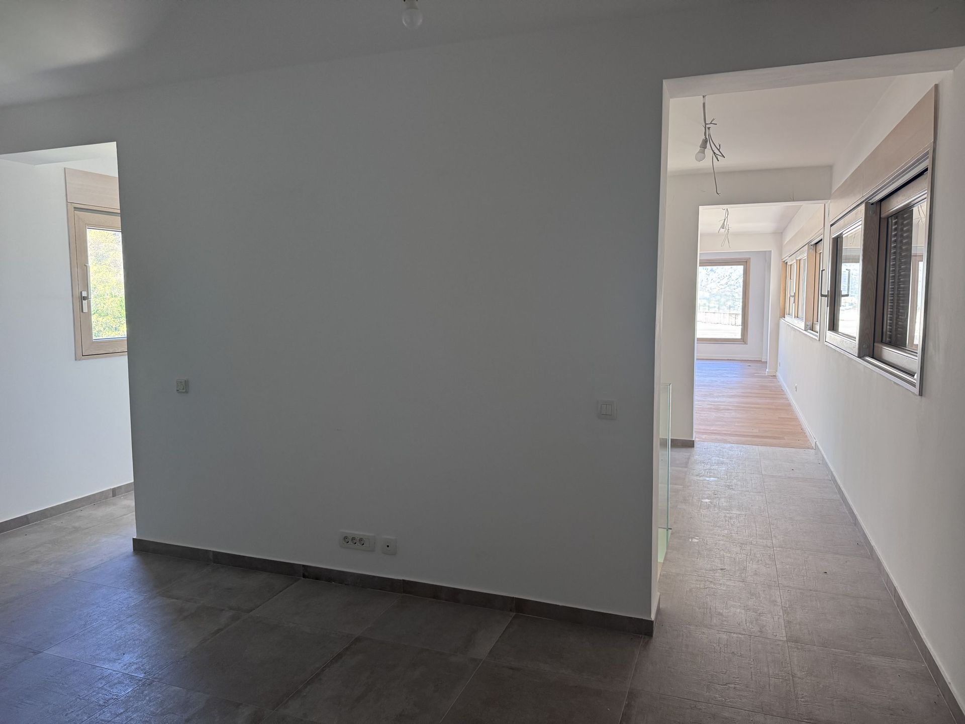 Living room interior in a duplex, Kotor, Montenegro: light finishes, tiled floor, and panoramic windows in a new house.