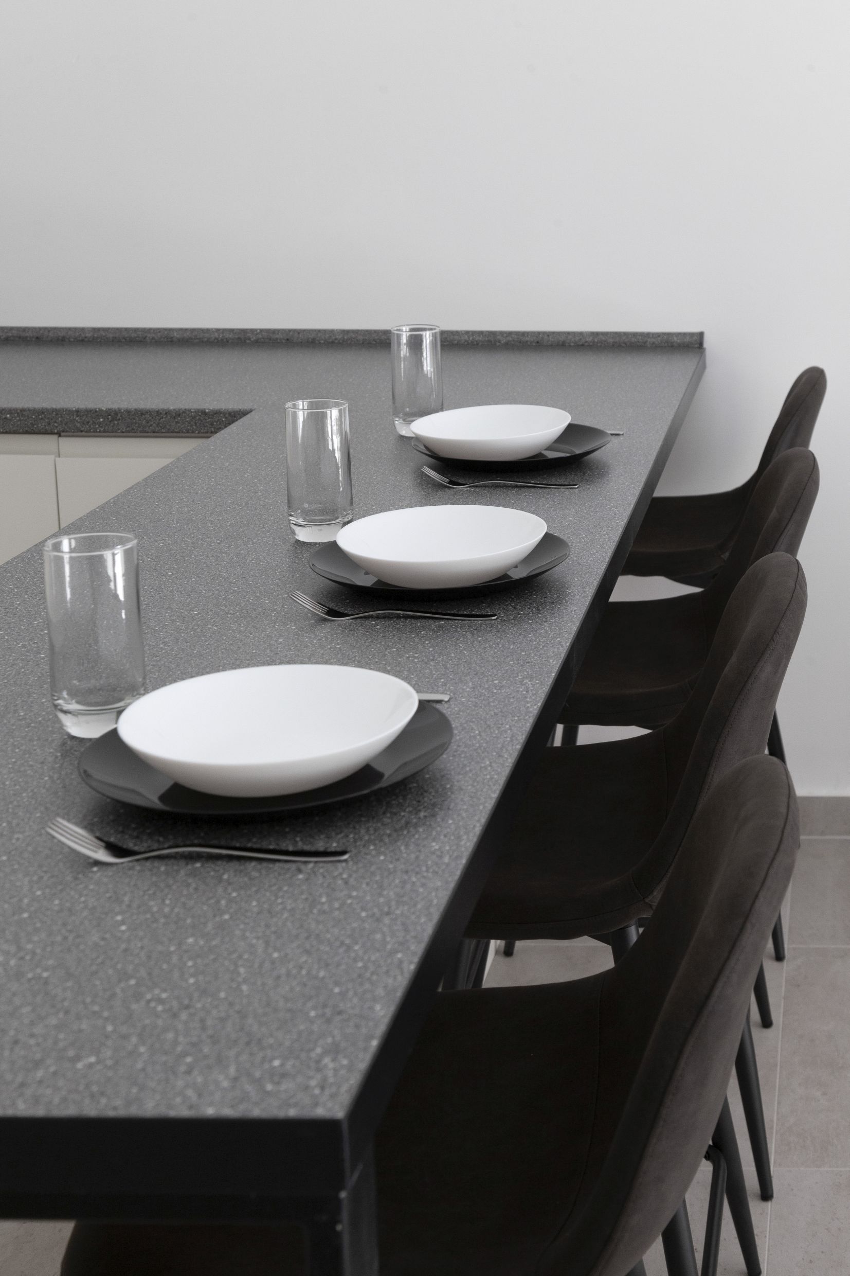 Modern kitchen in an apartment in Kotor, Montenegro: a breakfast bar set for serving, dark chairs, and a stylish interior.
