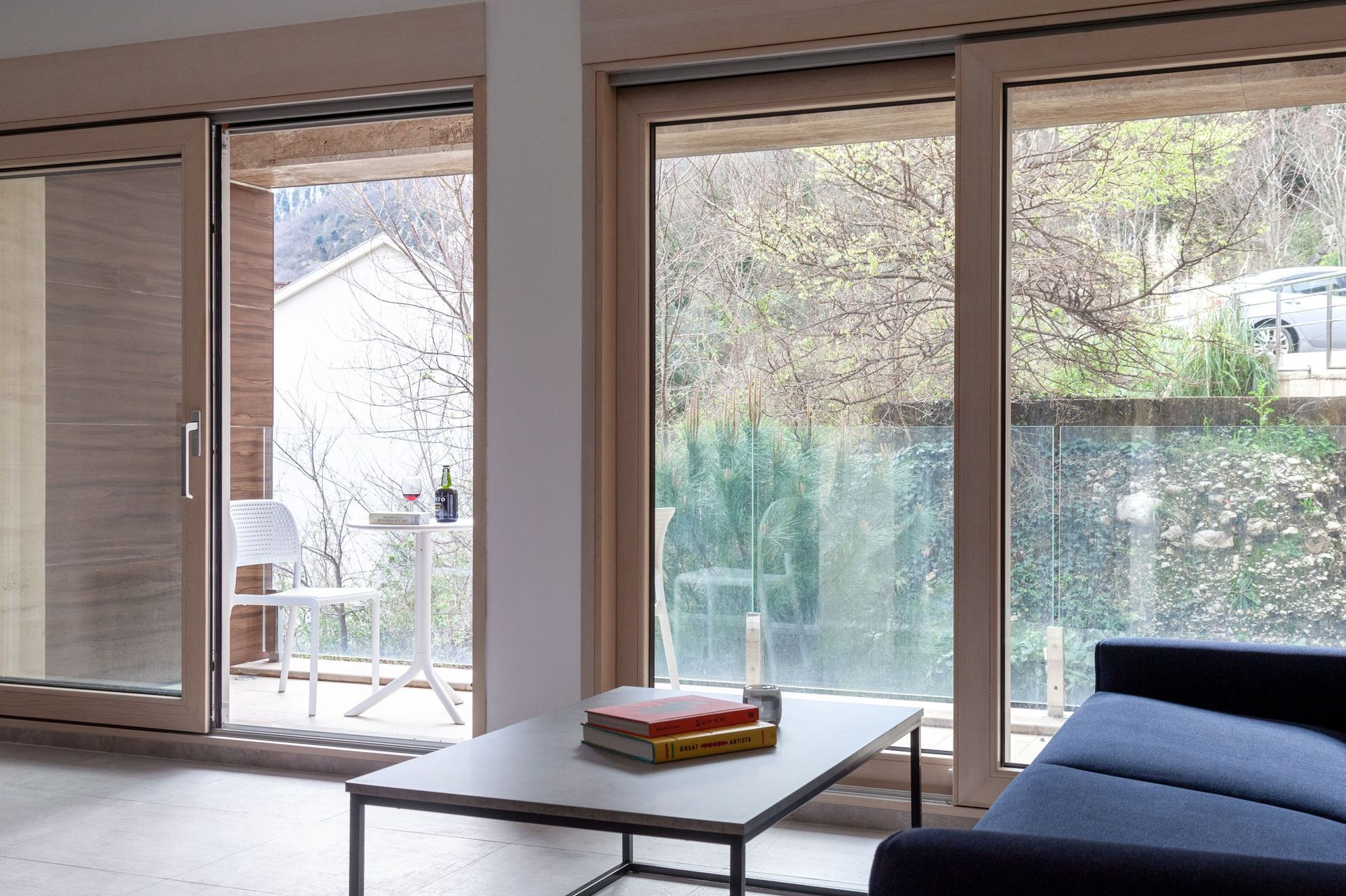 Living room with panoramic windows and access to the terrace in an apartment in Kotor, Montenegro: modern interior and a view.