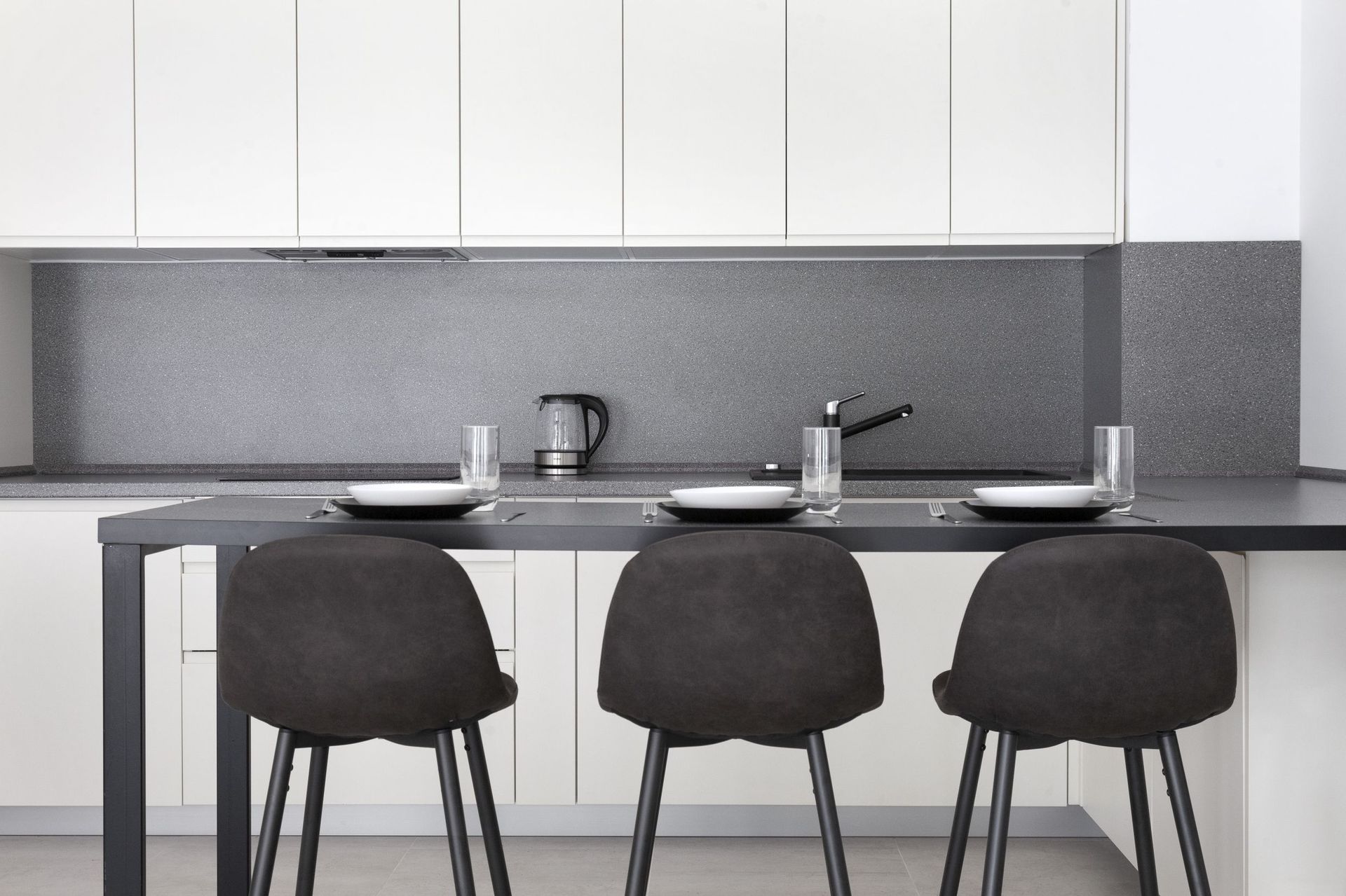 Modern kitchen with white cabinets, a gray countertop, and a breakfast bar in an apartment, Kotor, Montenegro.