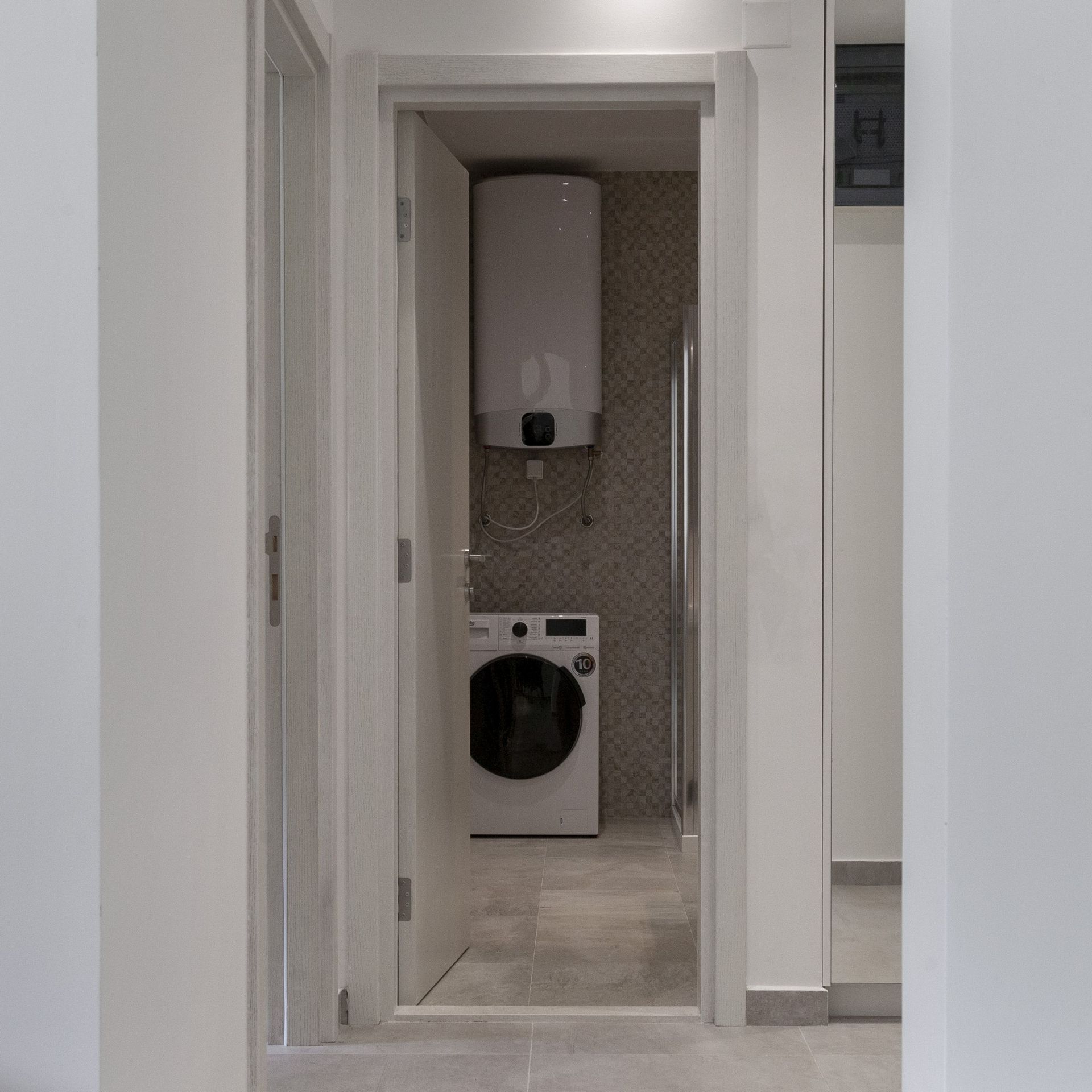 Bathroom in an apartment in Kotor, Montenegro: washing machine, boiler, and shower cabin in a modern interior.
