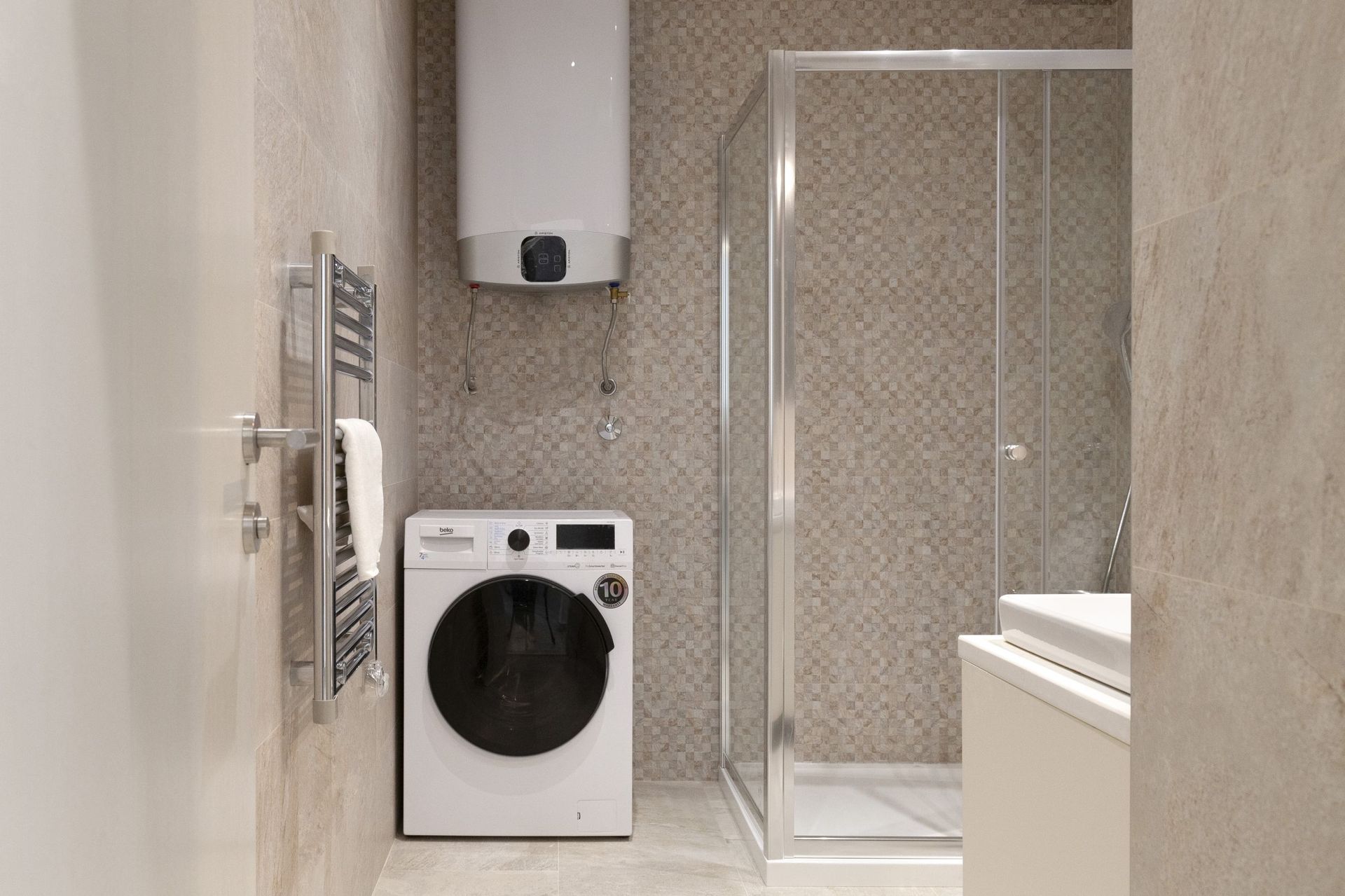 Modern bathroom in an apartment in Kotor, Montenegro: shower cabin, washing machine, and water heater.