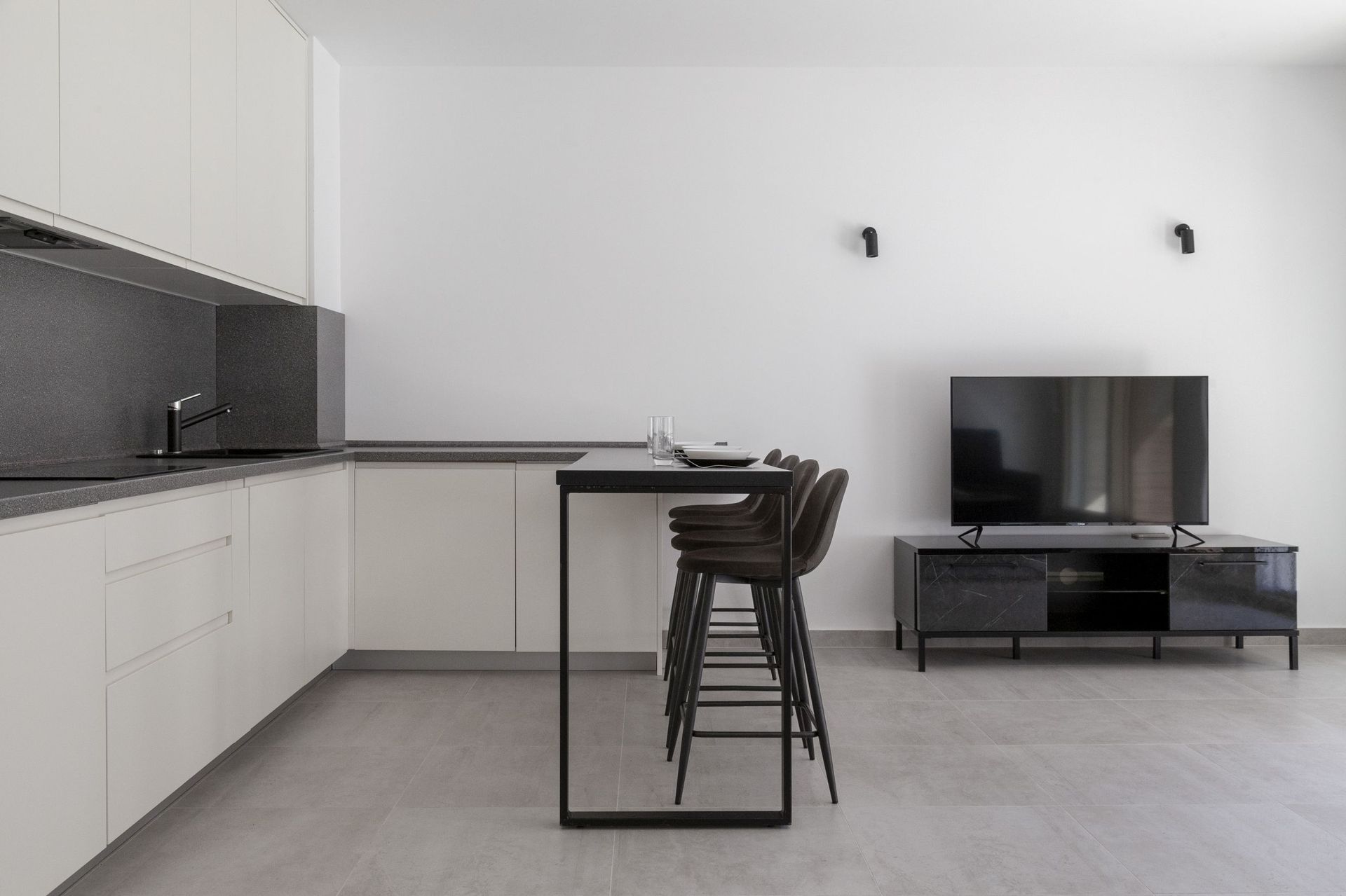 Modern kitchen-living room with a bar counter and TV area in an apartment, Kotor, Montenegro. Minimalist interior.