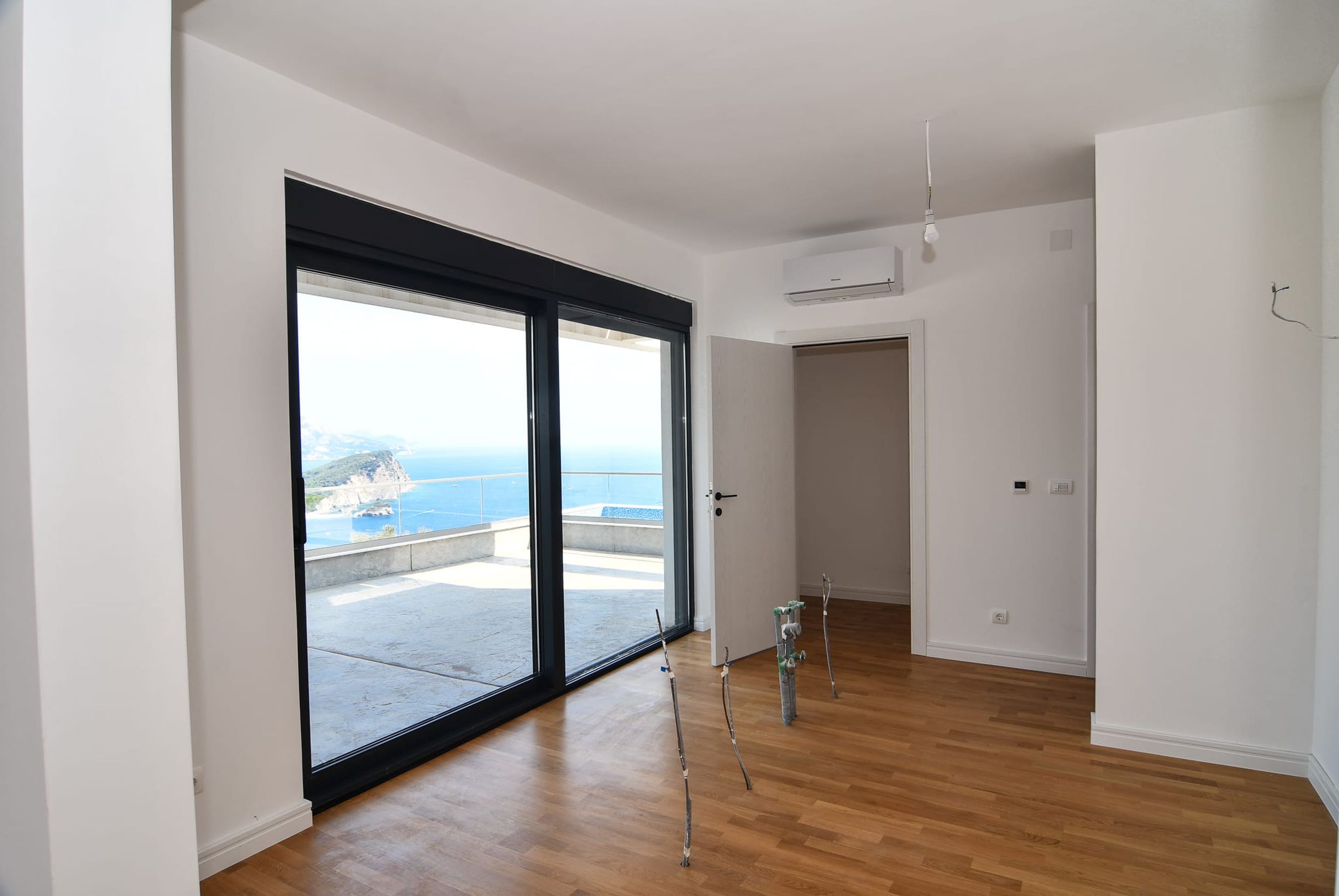 Living room in a villa in Budva, Montenegro: panoramic windows with sea views, a terrace, and bright interior finishes.
