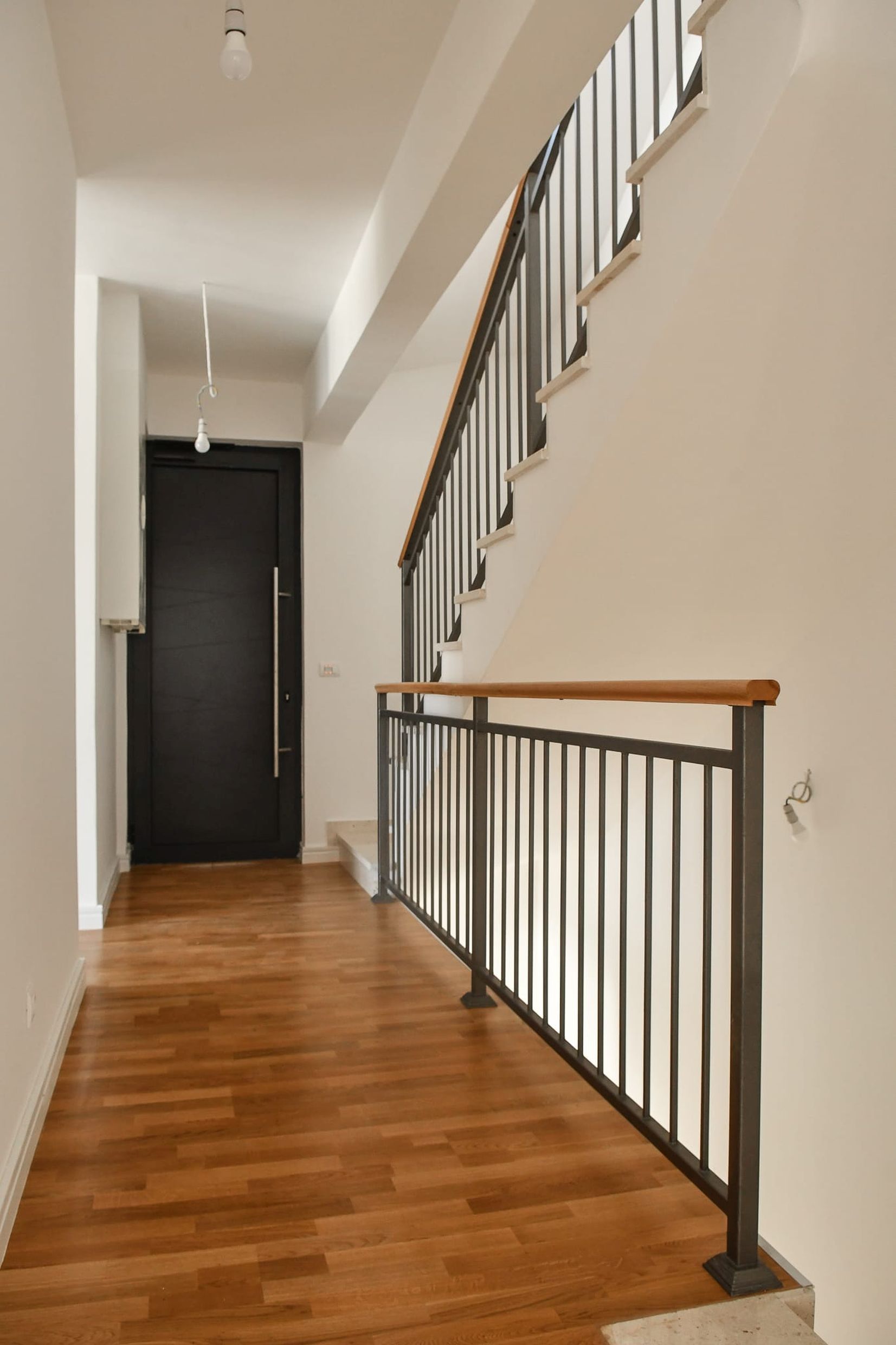 Villa interior in Budva, Montenegro: a modern staircase with metal railings and a wooden floor in the hall.
