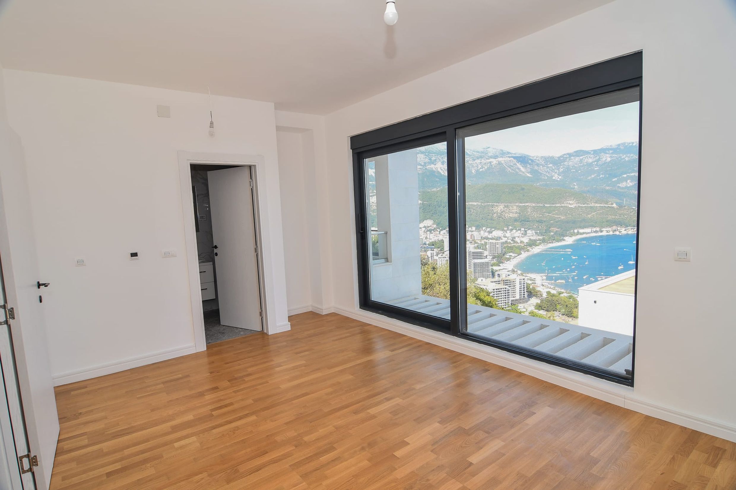 Bright bedroom in a villa in Budva, Montenegro, with panoramic views of the sea and mountains and parquet flooring.