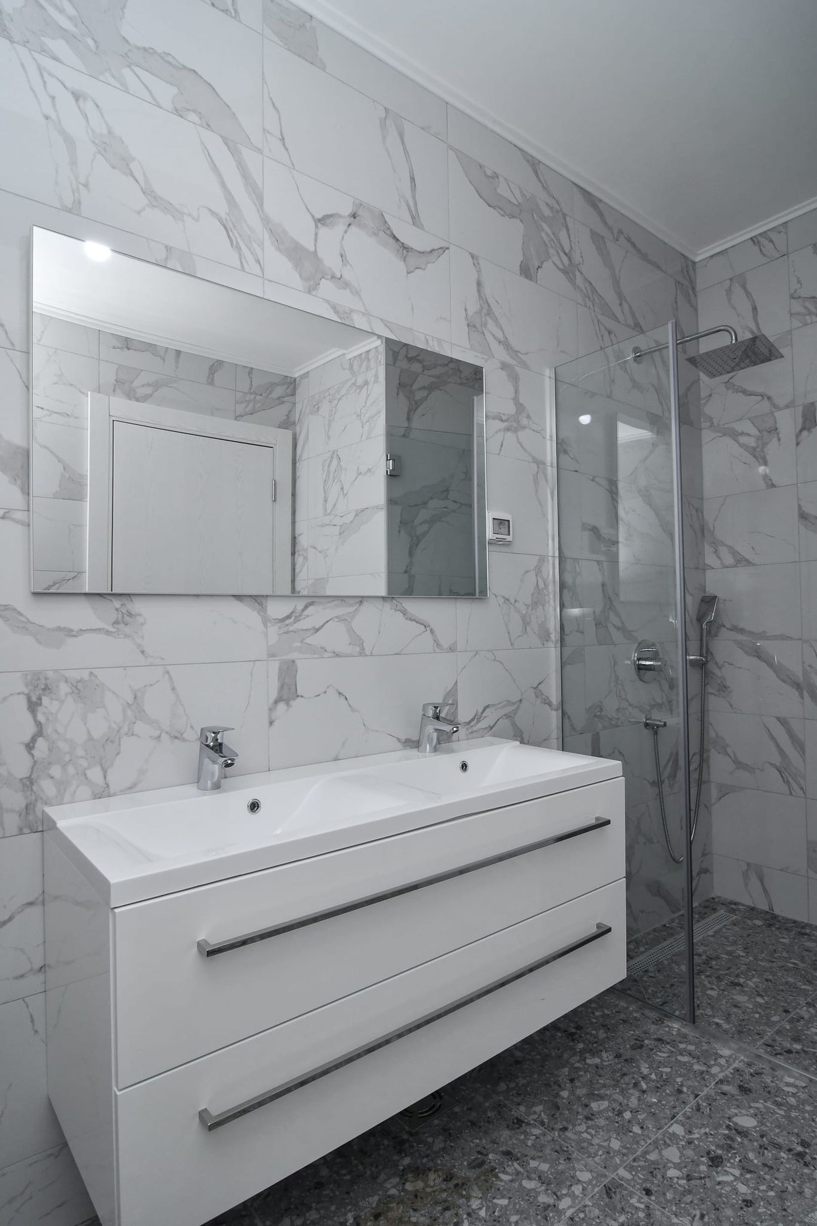 Modern bathroom with a shower cabin and double sink in a villa in Budva, Montenegro, marble finish.