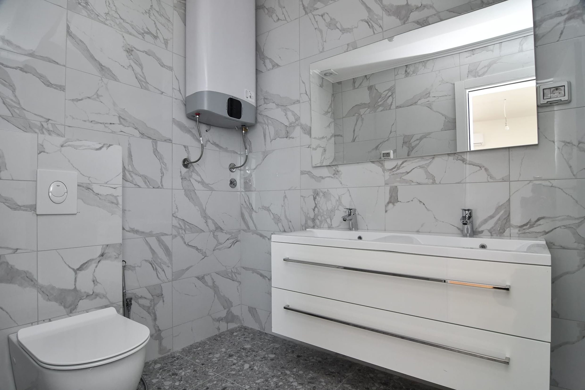Modern bathroom with marble-style finishes in a villa, Budva, Montenegro: vanity with sink and boiler.