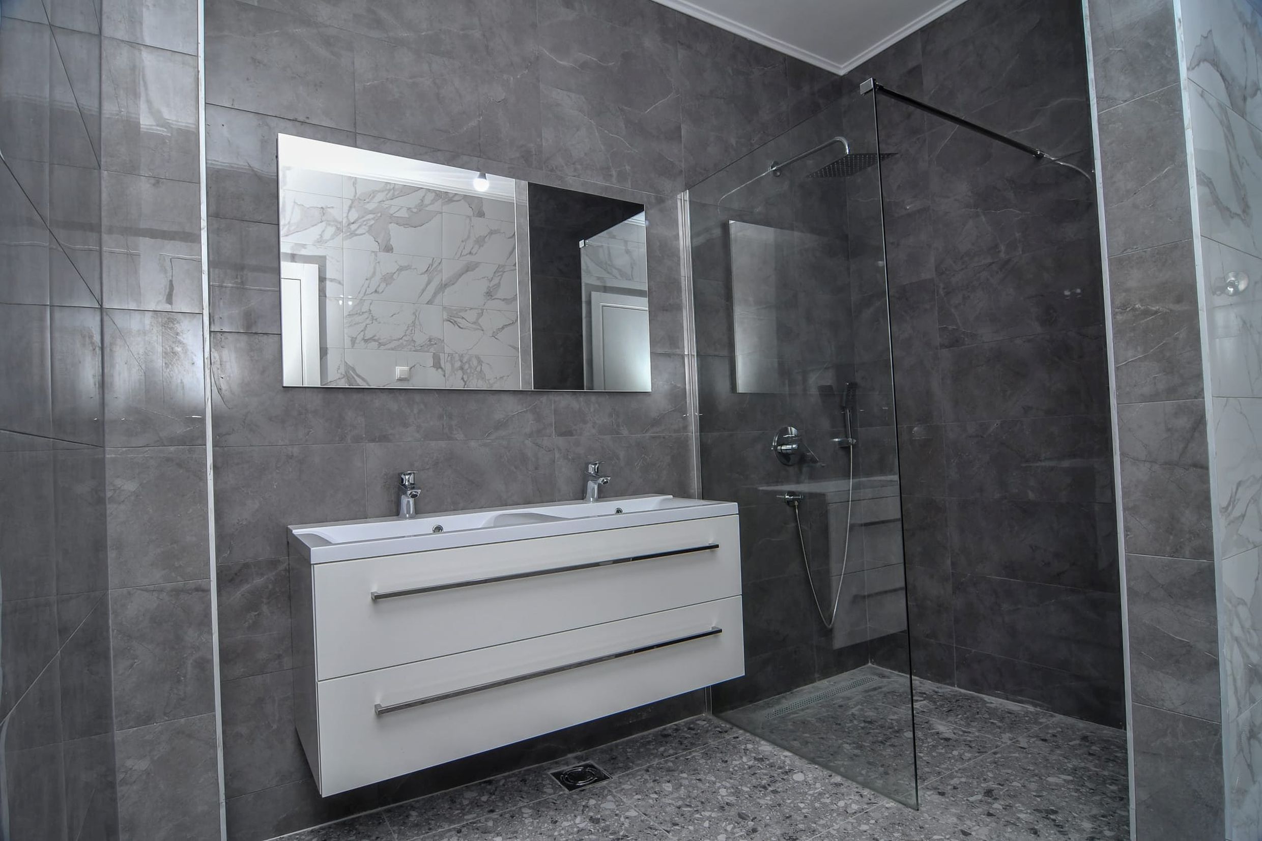 Modern bathroom with a shower cabin and gray tiles in a villa in Budva, Montenegro.
