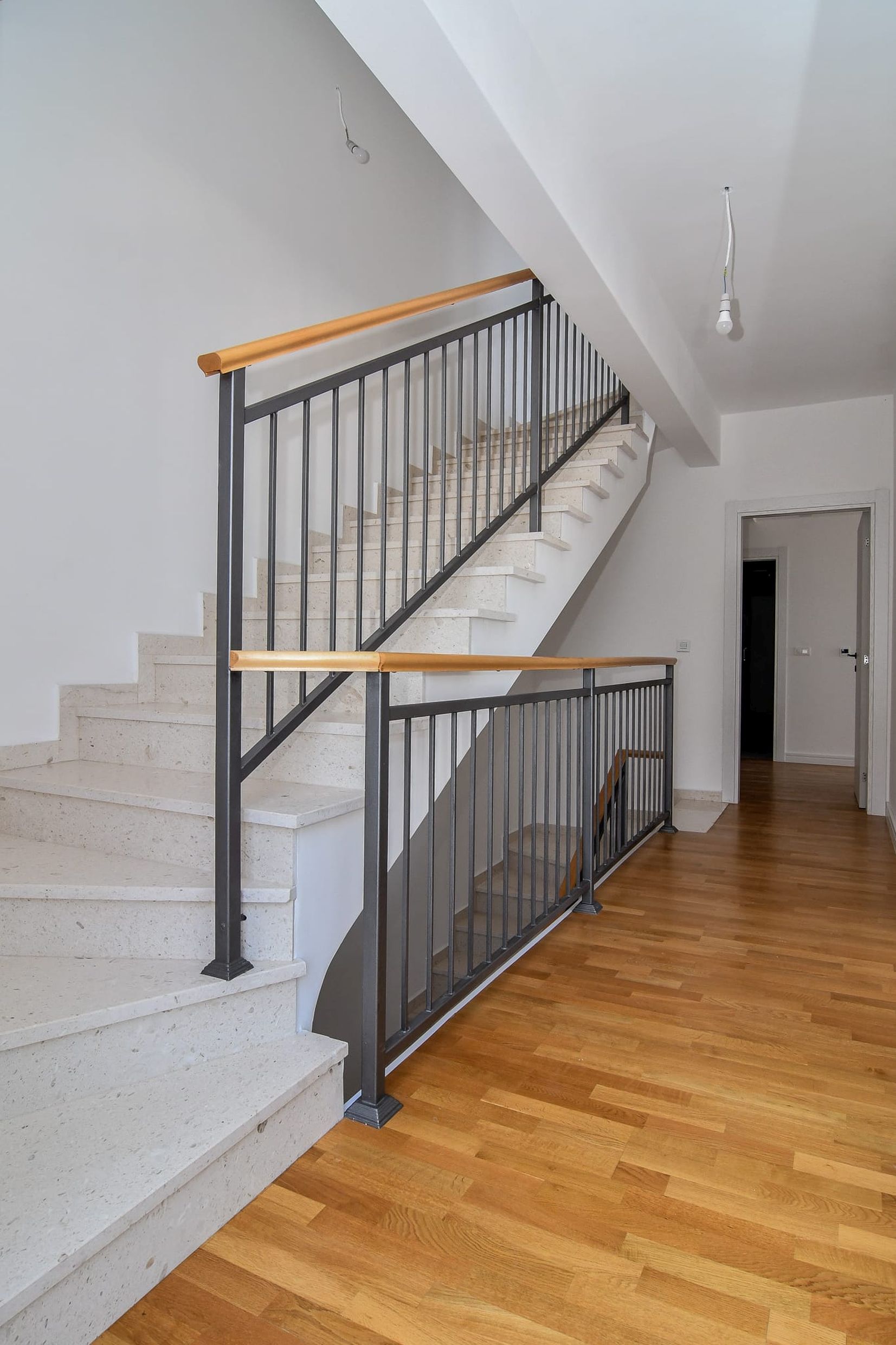 Staircase with stone steps and wrought-iron railings in the interior of a modern villa in Budva, Montenegro.