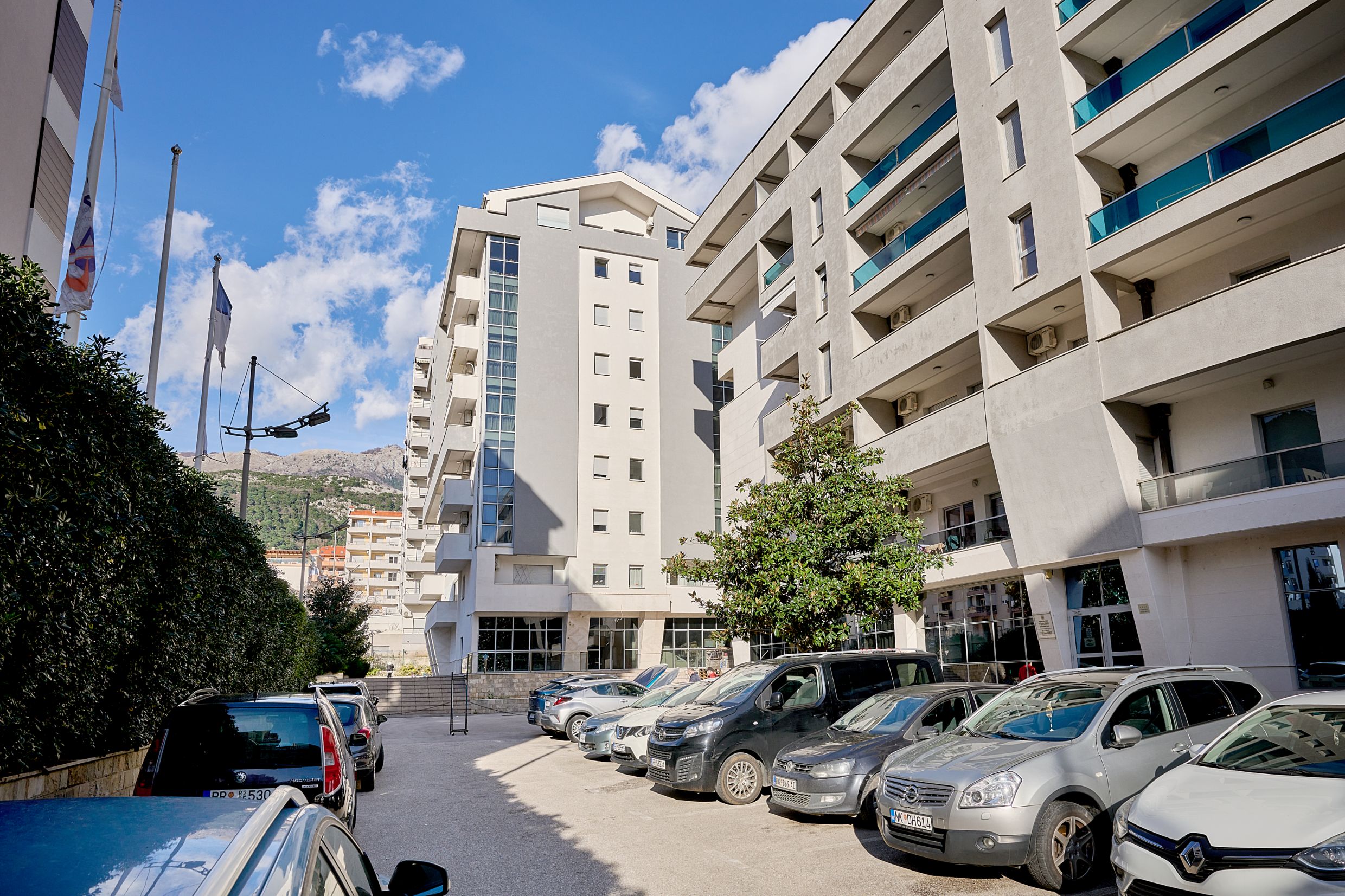 Modern residential complex with parking in Budva, Montenegro: building facade with balconies and mountain view.