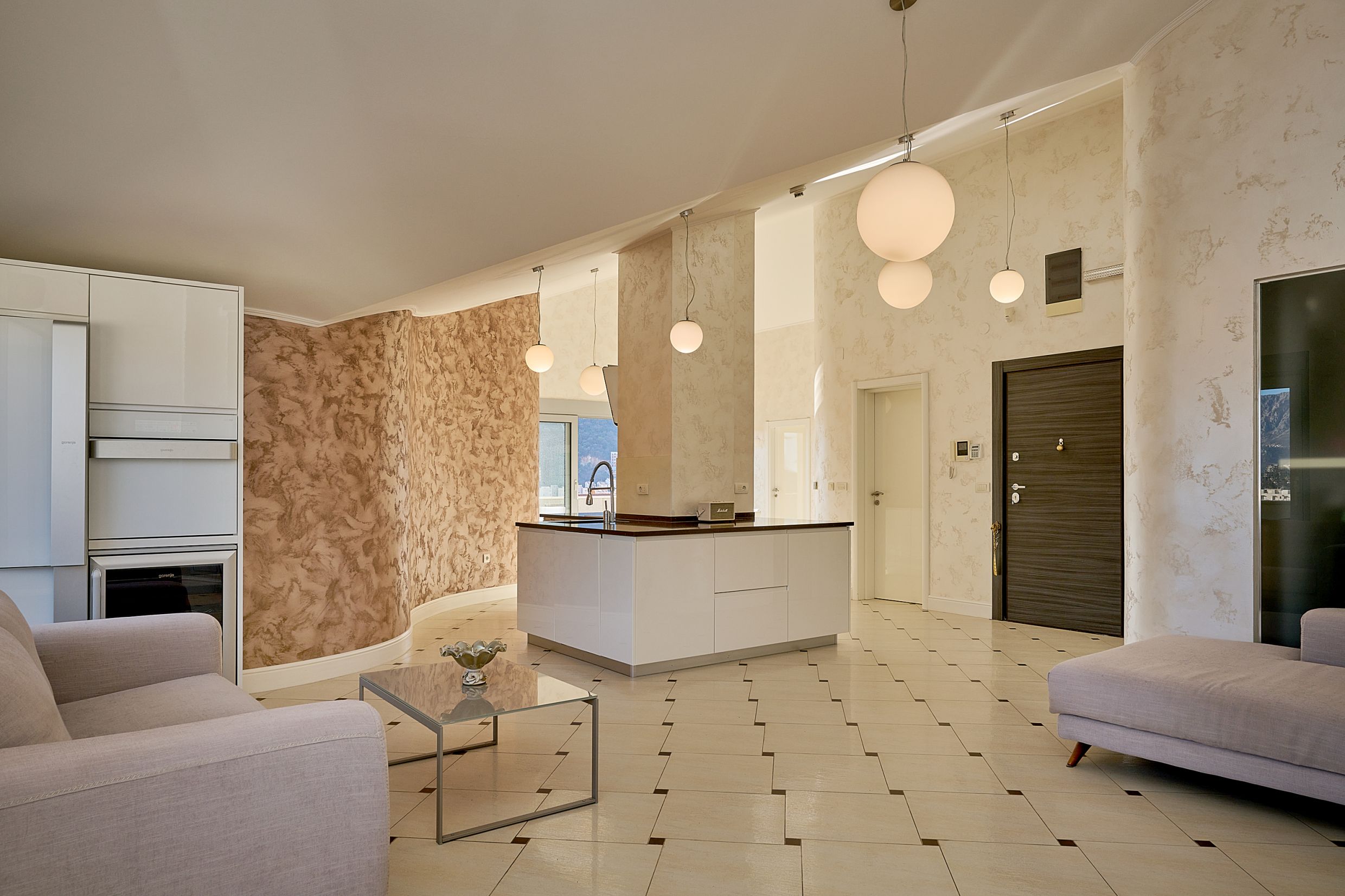 Modern living room with an island kitchen in an apartment in Budva, Montenegro: bright interior, tile, and stylish decor.