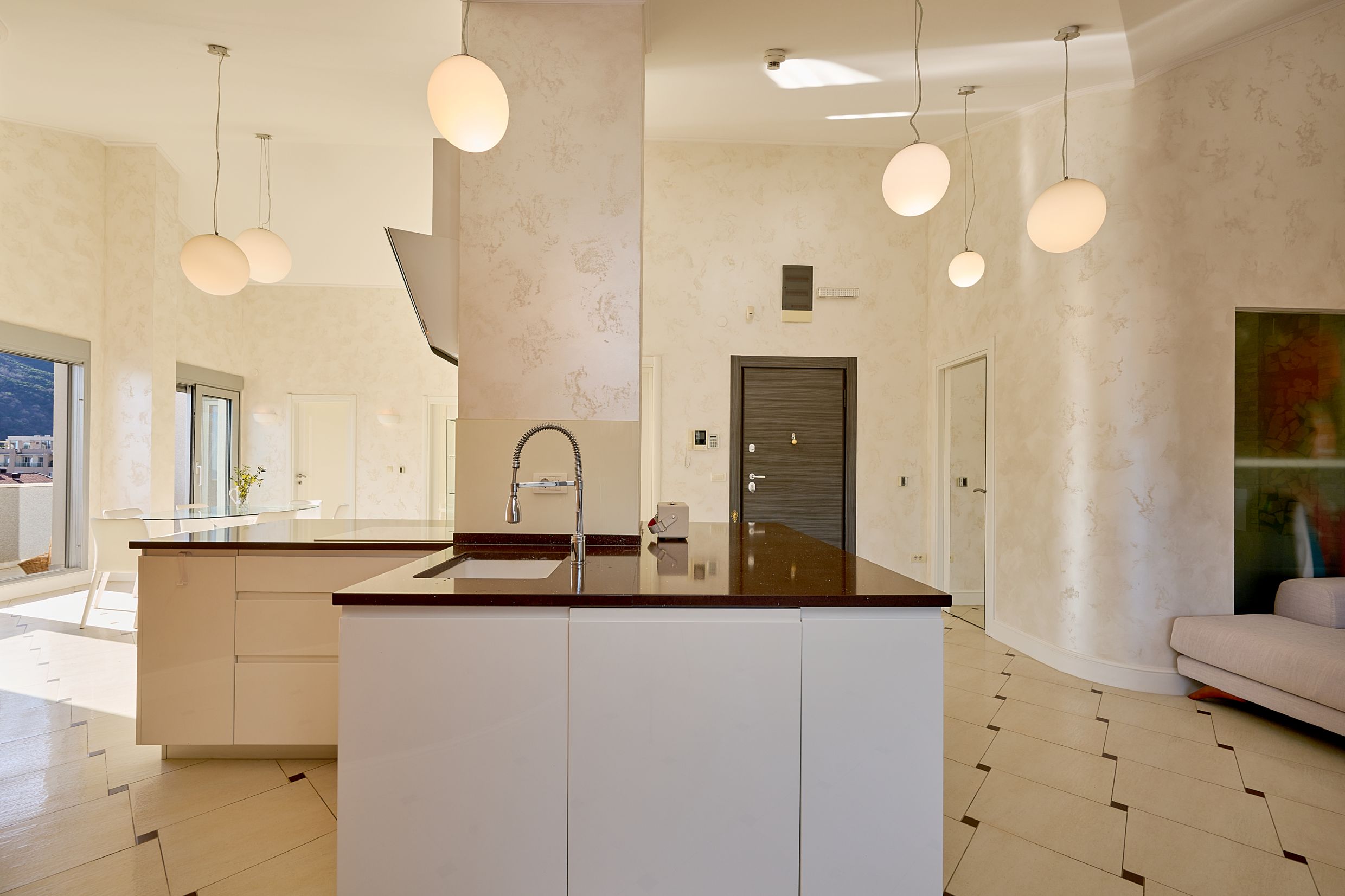 Modern kitchen with an island in an apartment in Budva, Montenegro: bright interior, high-quality finishes, and a view from the window.