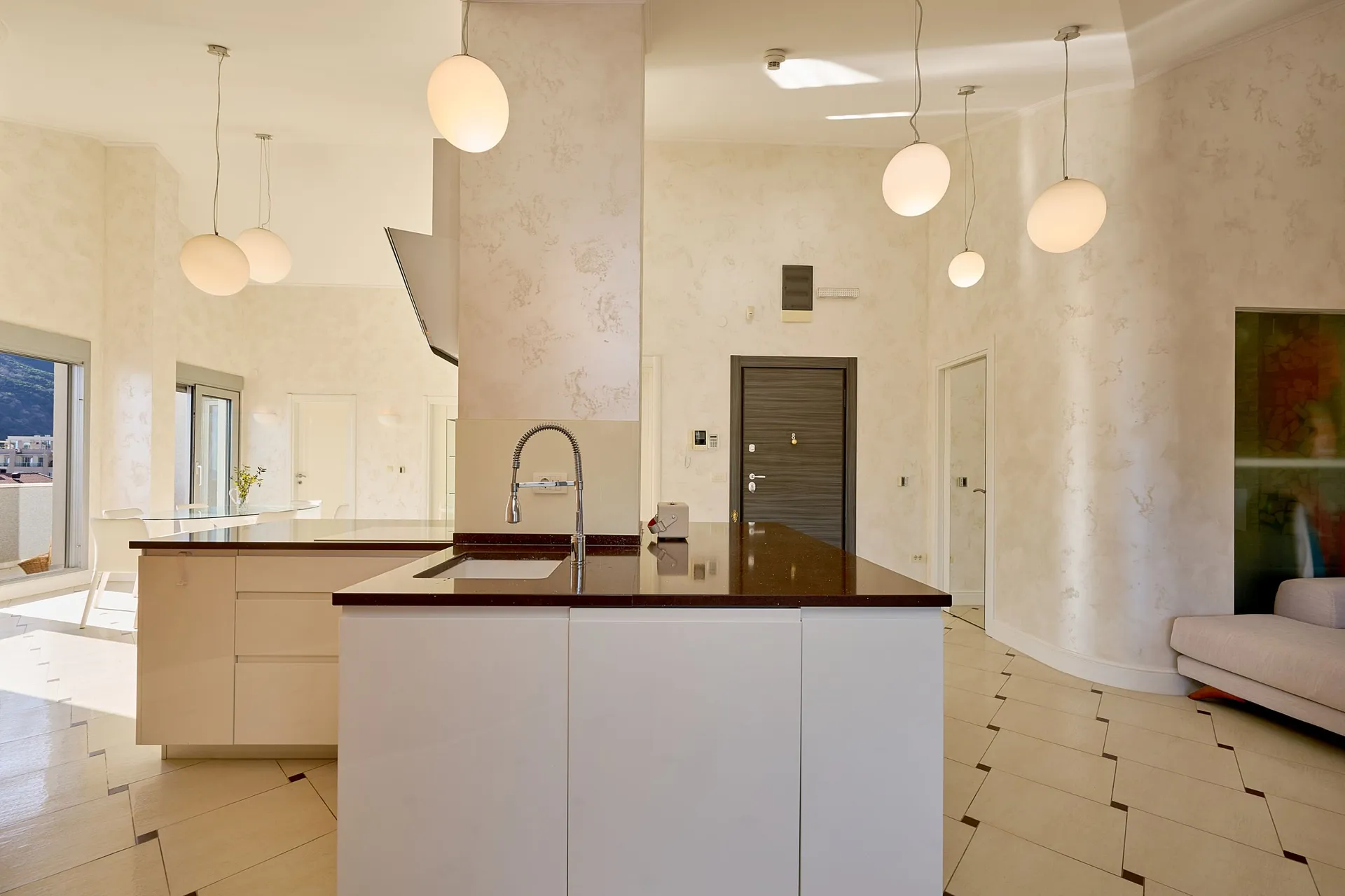 Modern kitchen featuring a white island, dark countertop, and multiple hanging spherical pendant lights.