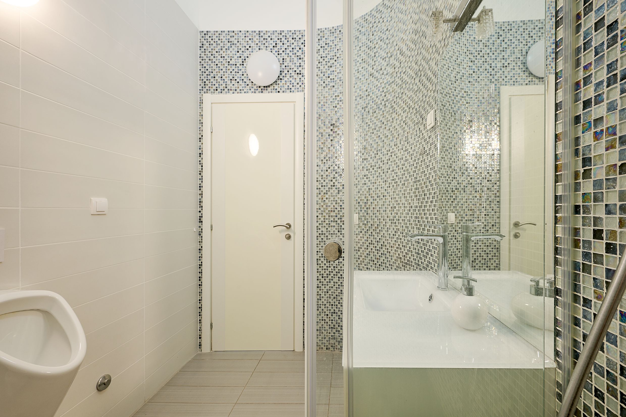 Modern bathroom in an apartment in Budva, Montenegro: shower cabin, mosaic tiles, and plumbing fixtures.