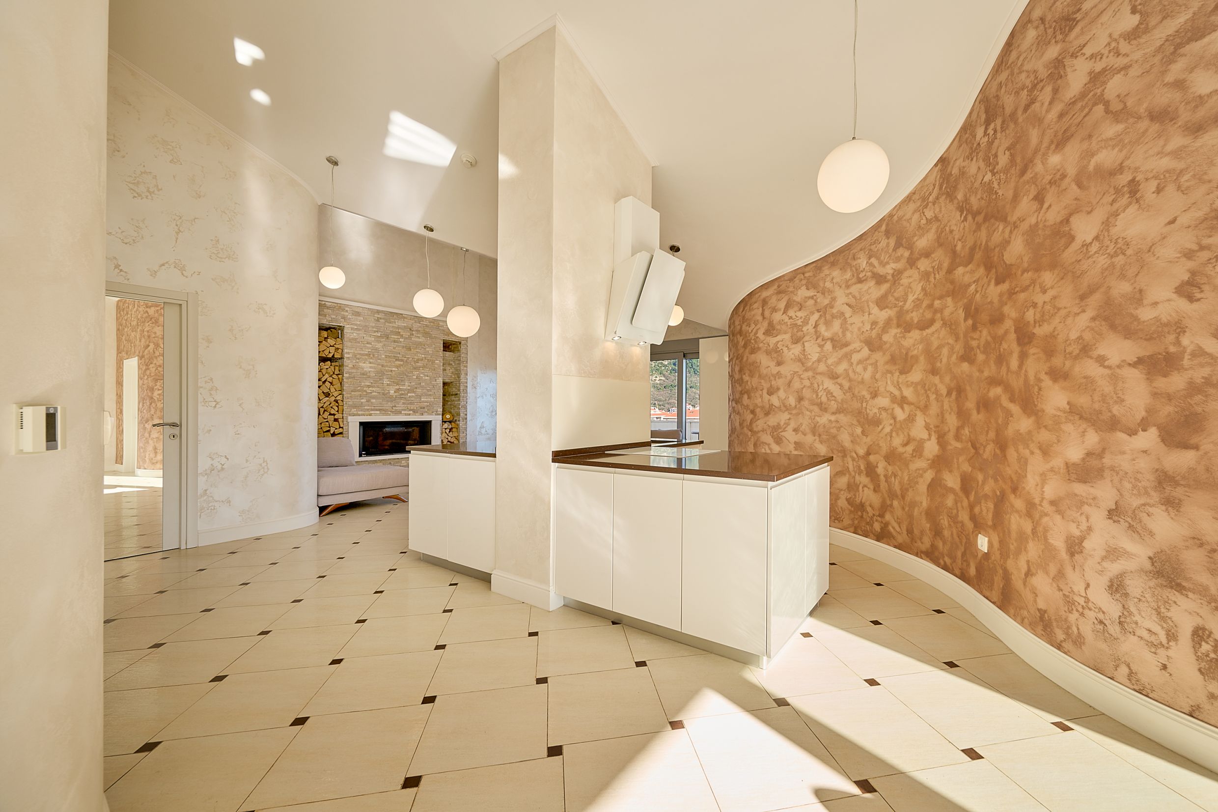 Modern kitchen-living room with a fireplace in an apartment in Budva, Montenegro: stylish interior, white furniture, and wall decor.