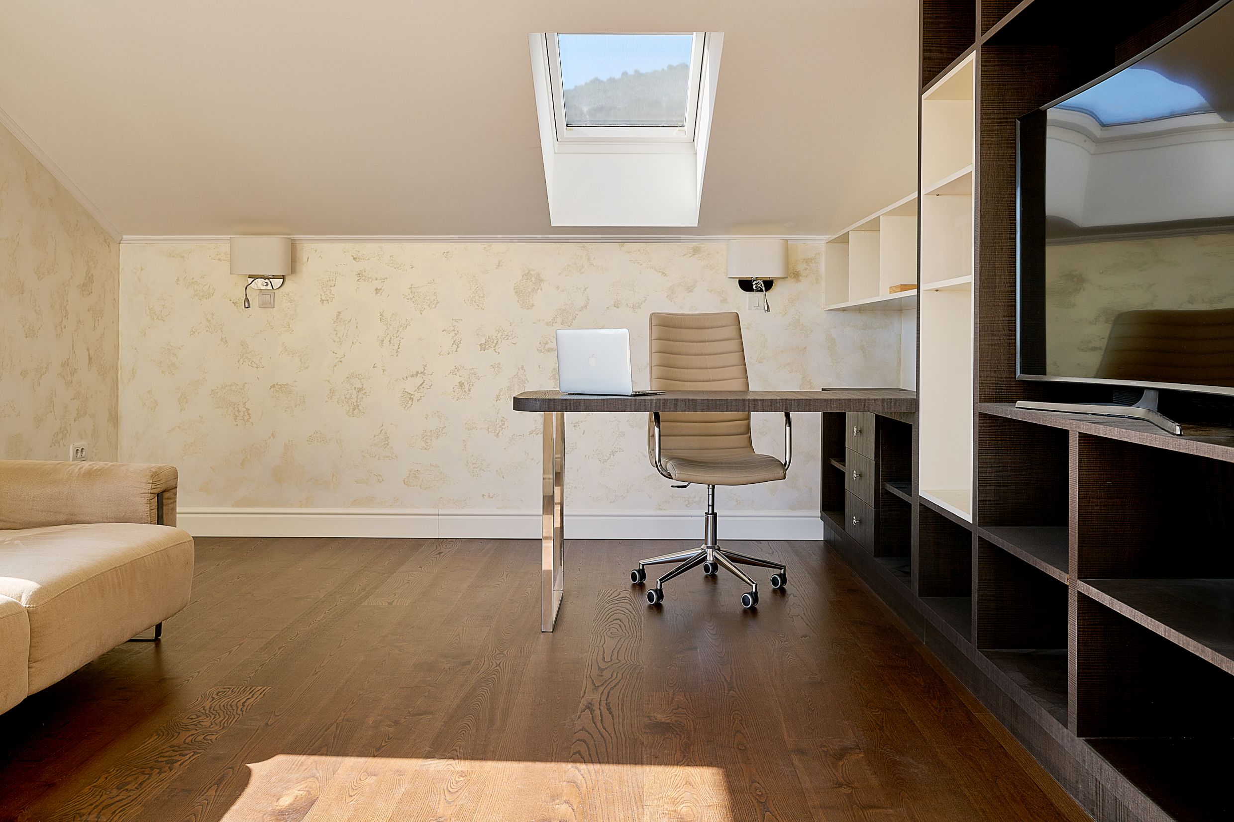 Home office in a loft apartment in Budva, Montenegro: desk, armchair, and shelving unit in a modern interior.