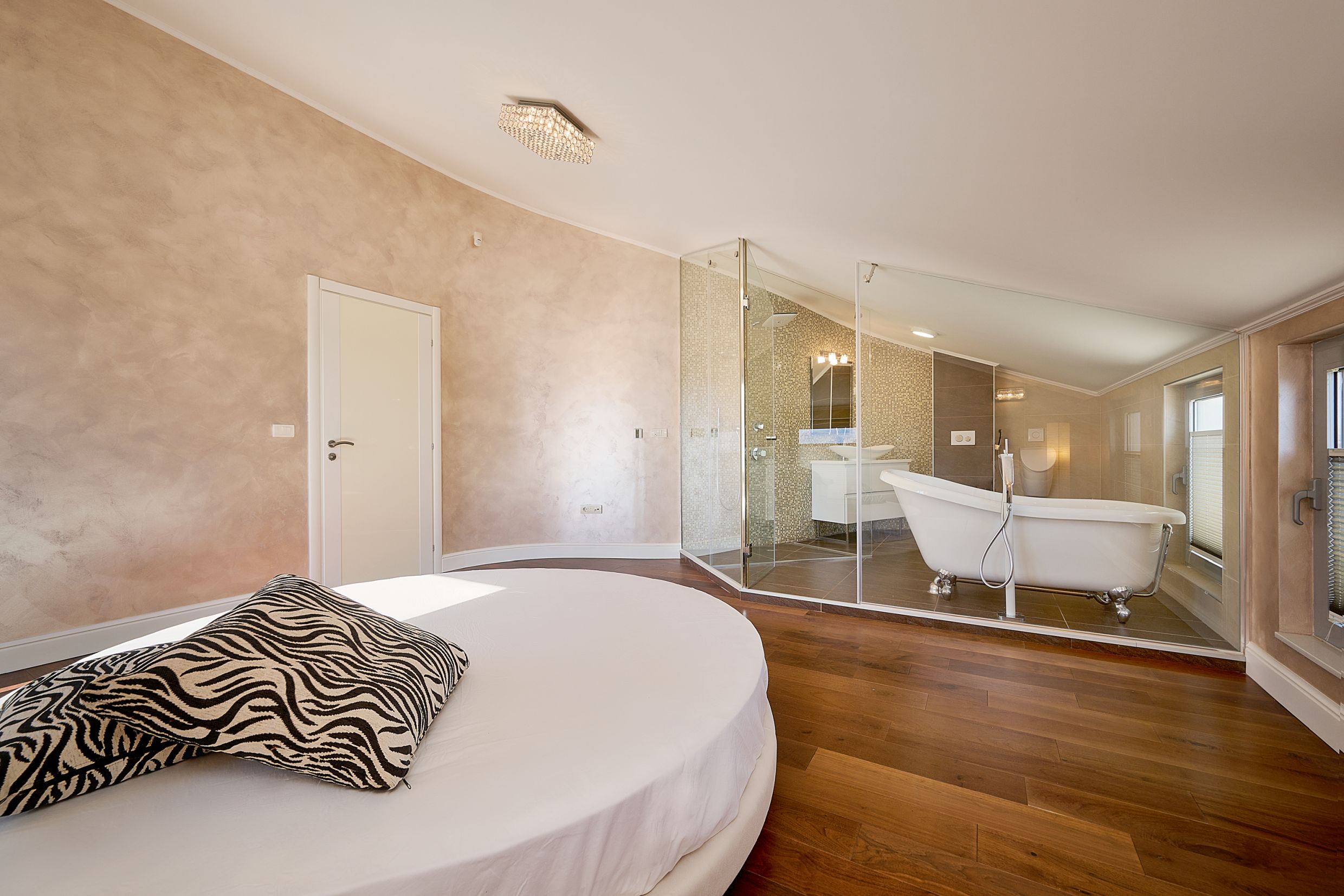 Bedroom with a round bed and a glass bathroom in an apartment in Budva, Montenegro. Modern interior.
