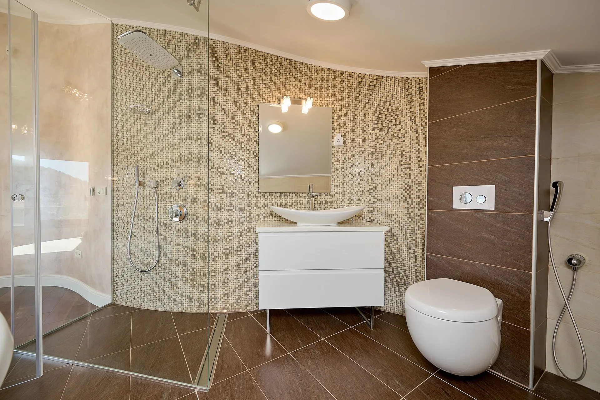 Modern bathroom featuring a mosaic-tiled shower, white vanity with vessel sink, and wall-mounted toilet.