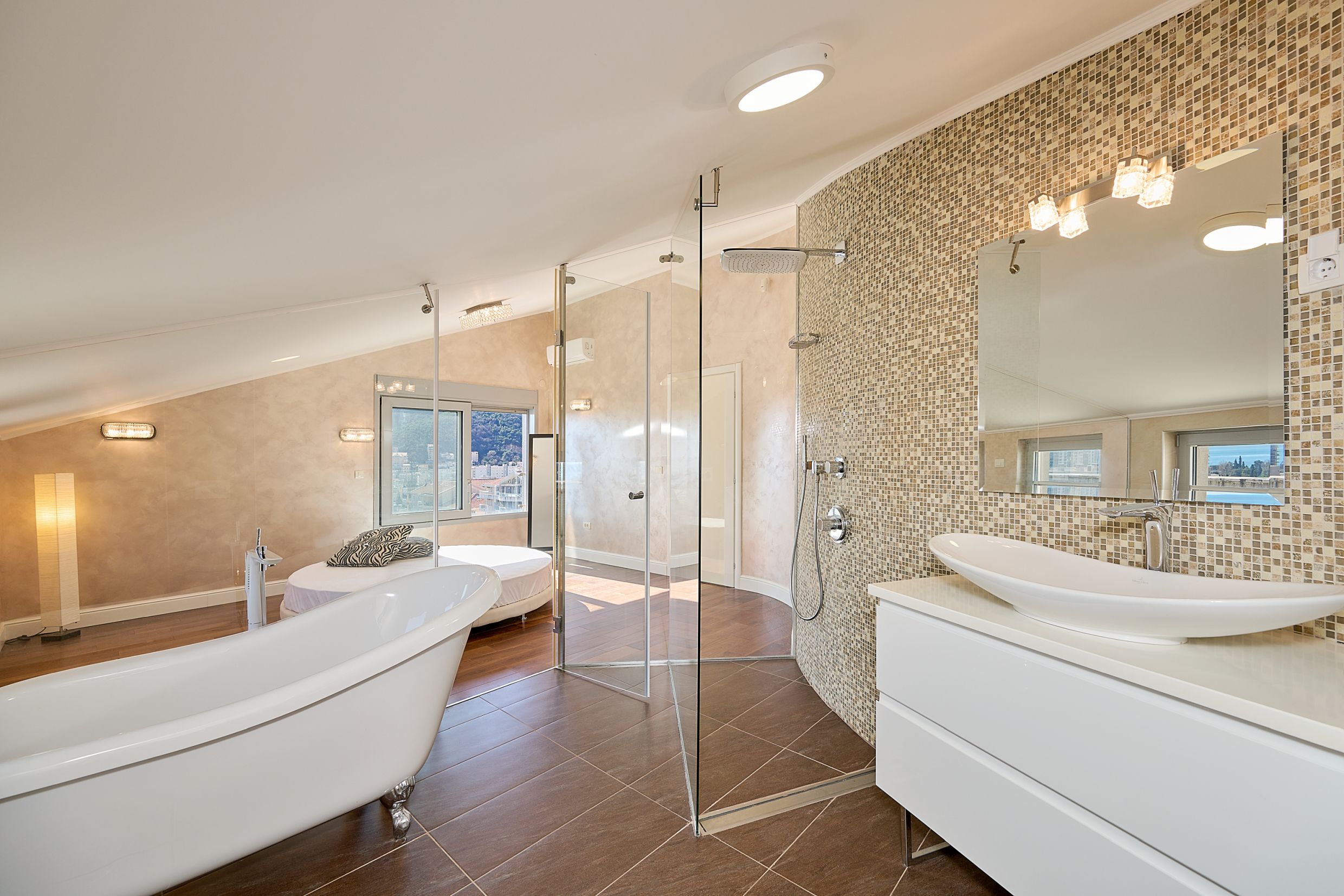 Modern bathroom in an apartment in Budva, Montenegro: freestanding bathtub, glass shower, and city view.