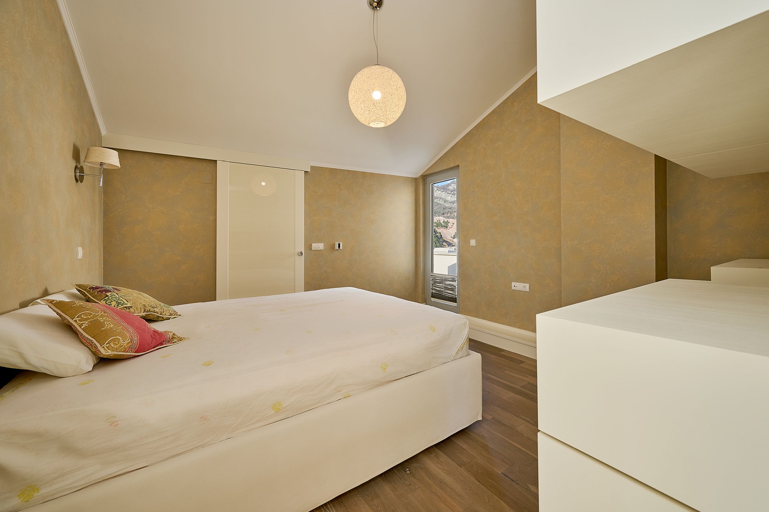 Cozy bedroom with a double bed in an apartment in Budva, Montenegro: stylish interior, mountain view, and parquet flooring.