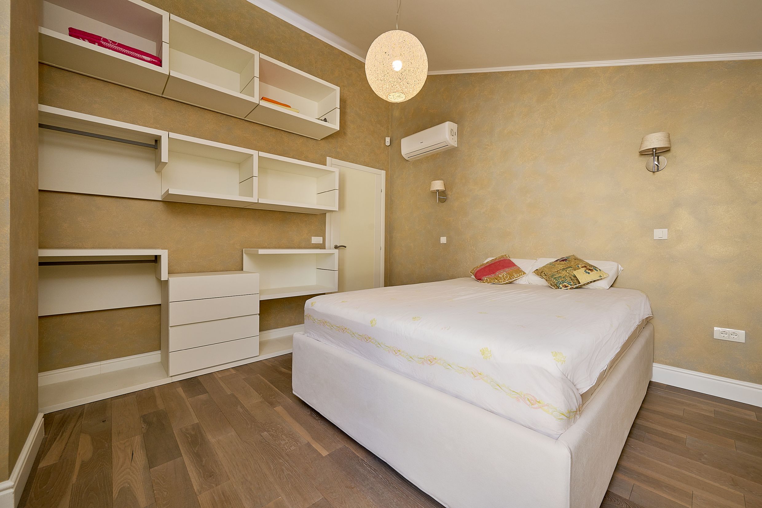 Bedroom with a double bed and built-in shelves in an apartment in Budva, Montenegro. Modern interior with air conditioning.