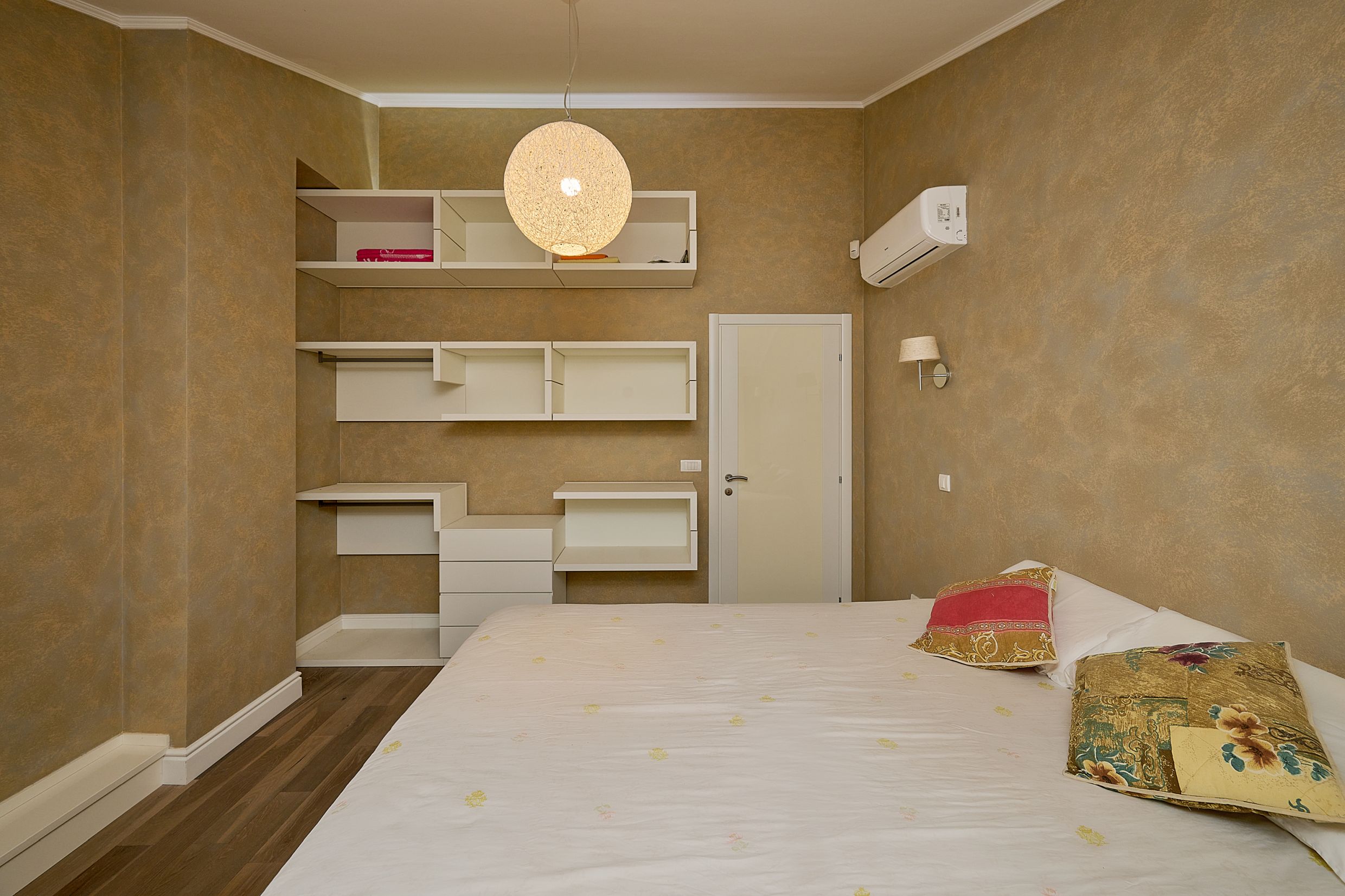 Bedroom in an apartment in Budva, Montenegro: double bed, open storage system, and air conditioner.