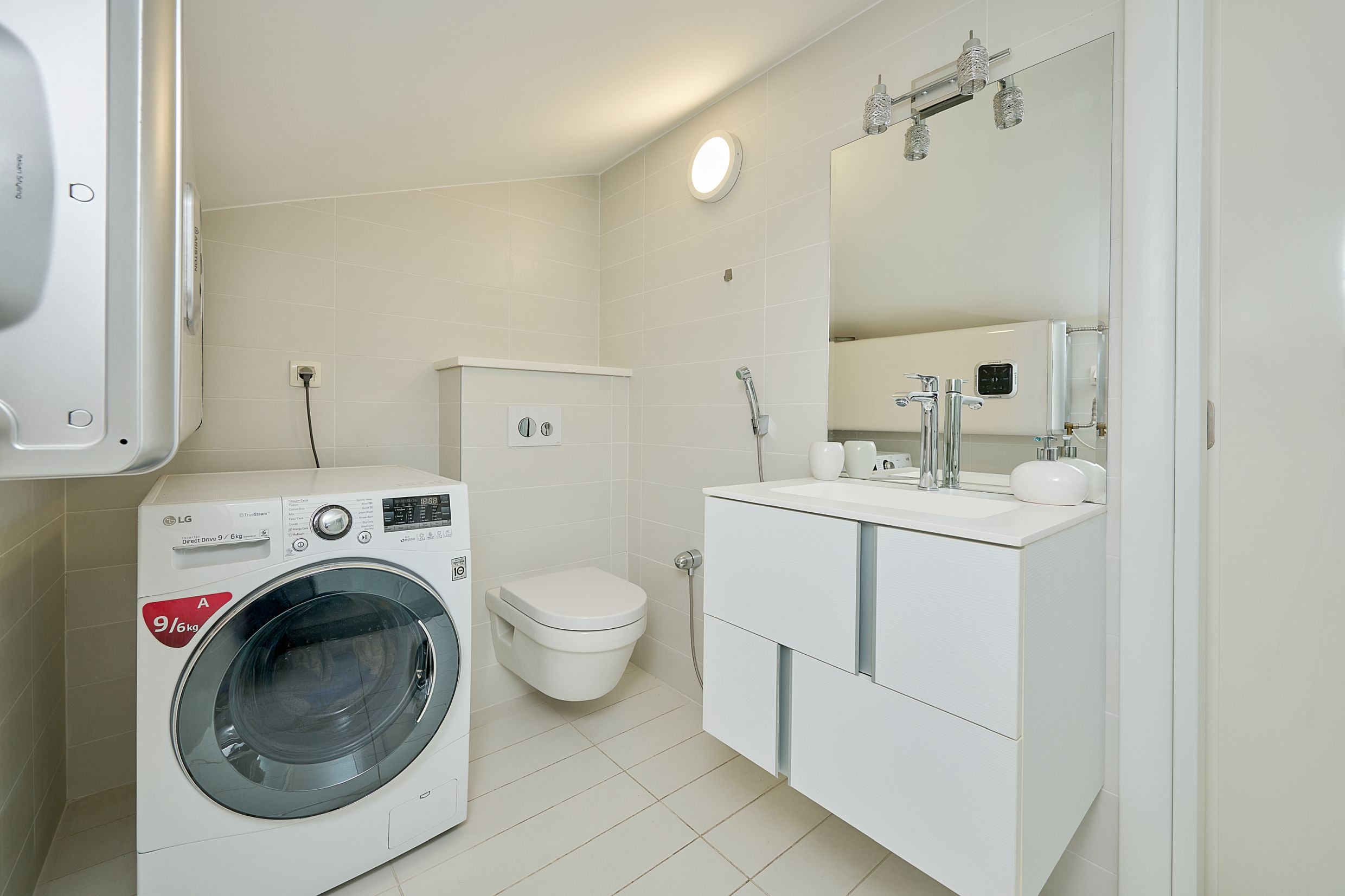 Modern bathroom in an apartment in Budva, Montenegro: wall-mounted toilet, vanity with sink, and LG washing machine.