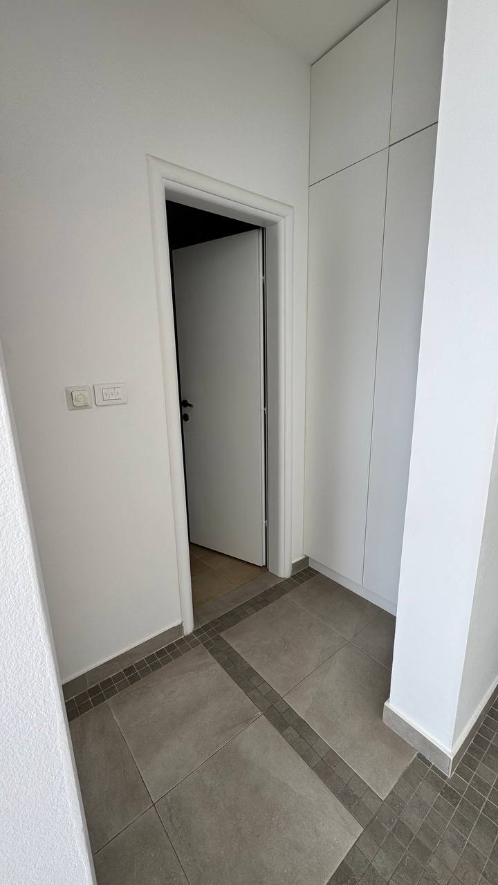 Modern hallway interior with a white built-in wardrobe and porcelain stoneware flooring in an apartment, Budva, Montenegro.