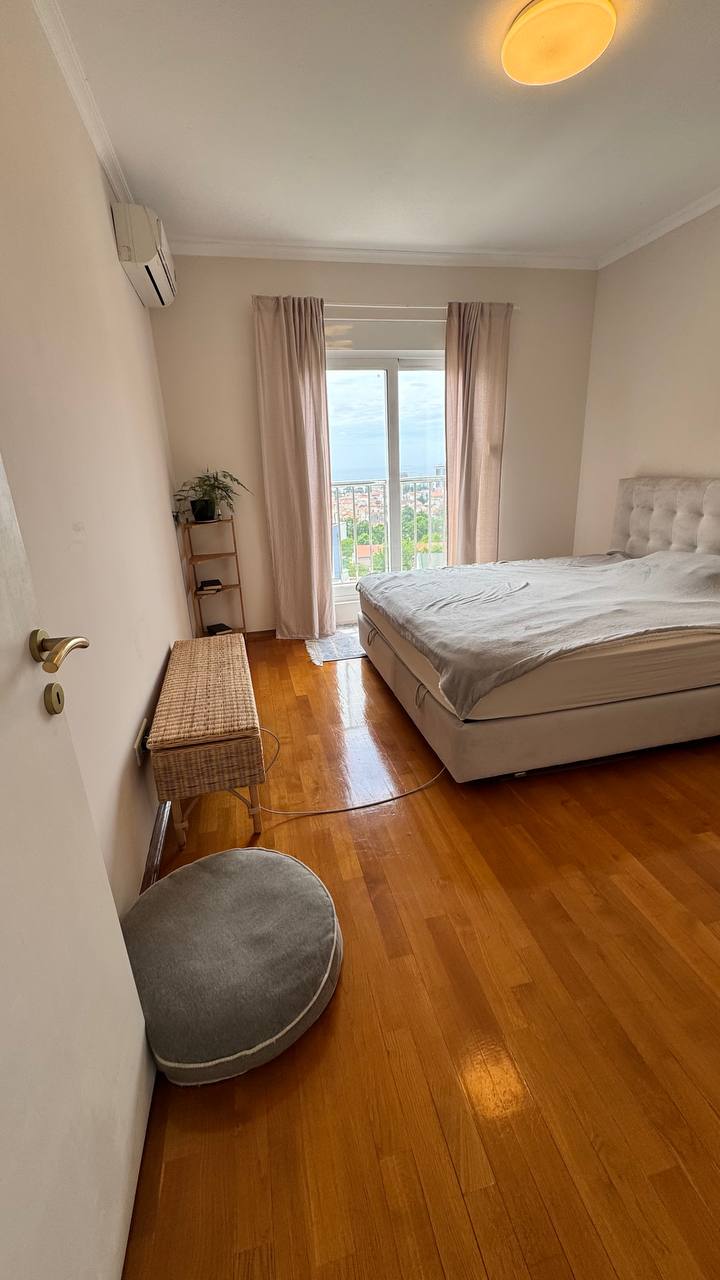 Cozy bedroom with a double bed, parquet flooring, and a sea view in an apartment in Budva, Montenegro.