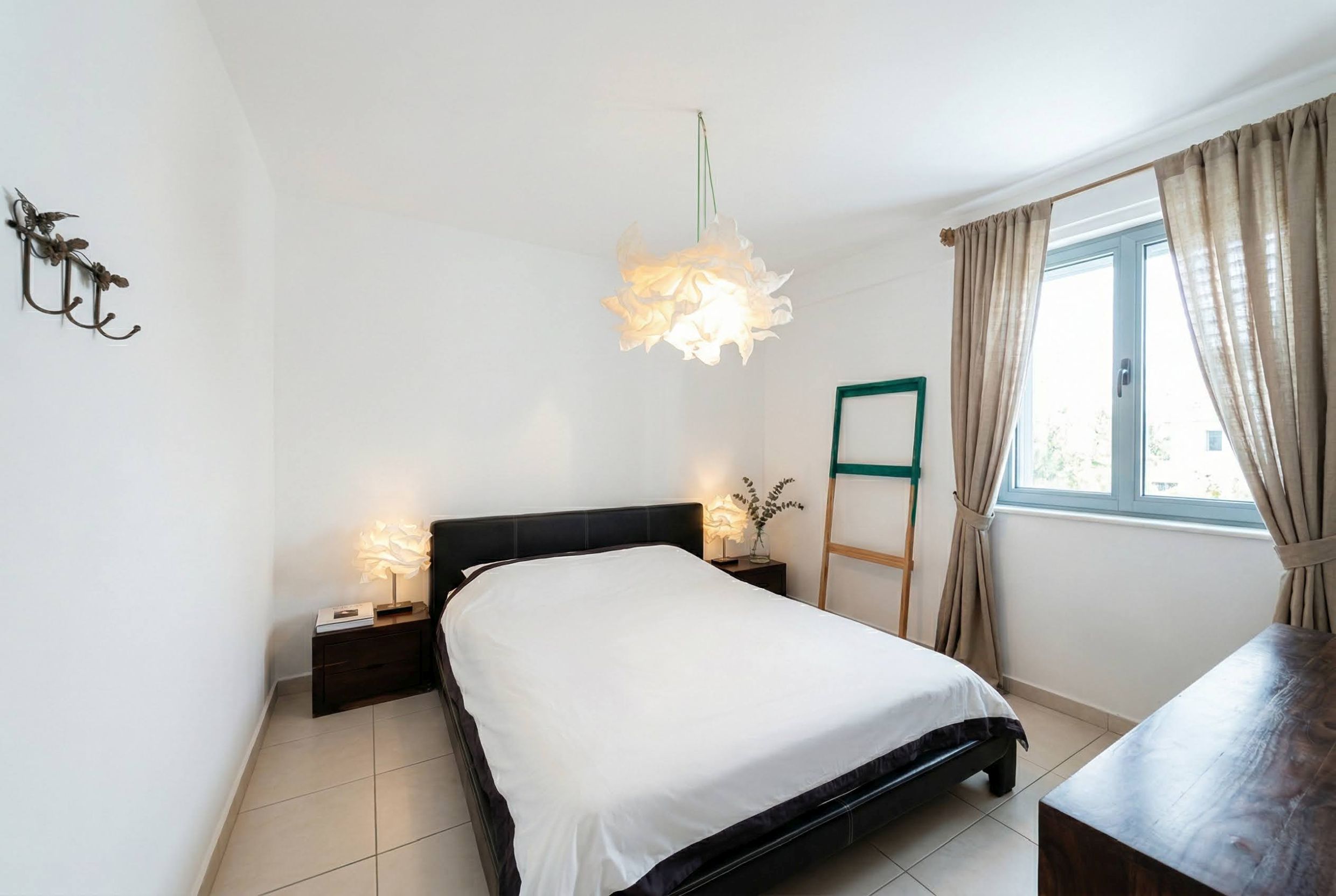 Bright bedroom in an apartment in Bečići, Montenegro: double bed, designer lamps, and tiled floor.