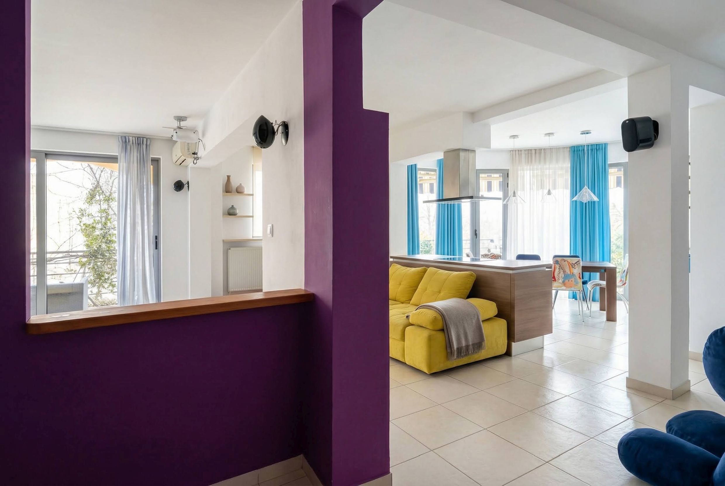 Living room with a yellow sofa and kitchen in a modern apartment in Bečići, Montenegro. Bright interior with vivid accents.